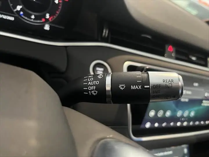 Gros plan sur la commande d'essuie-glace du Range Rover Evoque noir Santorini, avec tableau de bord et écran tactile en arrière-plan.