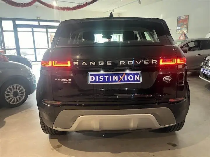 Vue arrière d'un Range Rover Evoque noir Santorini avec feux allumés et plaque Distinxion en concession.