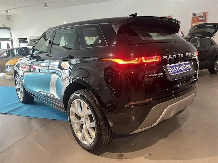 Vue 3/4 arrière d'un Range Rover Evoque noir Santorini avec feux arrière allumés en showroom.