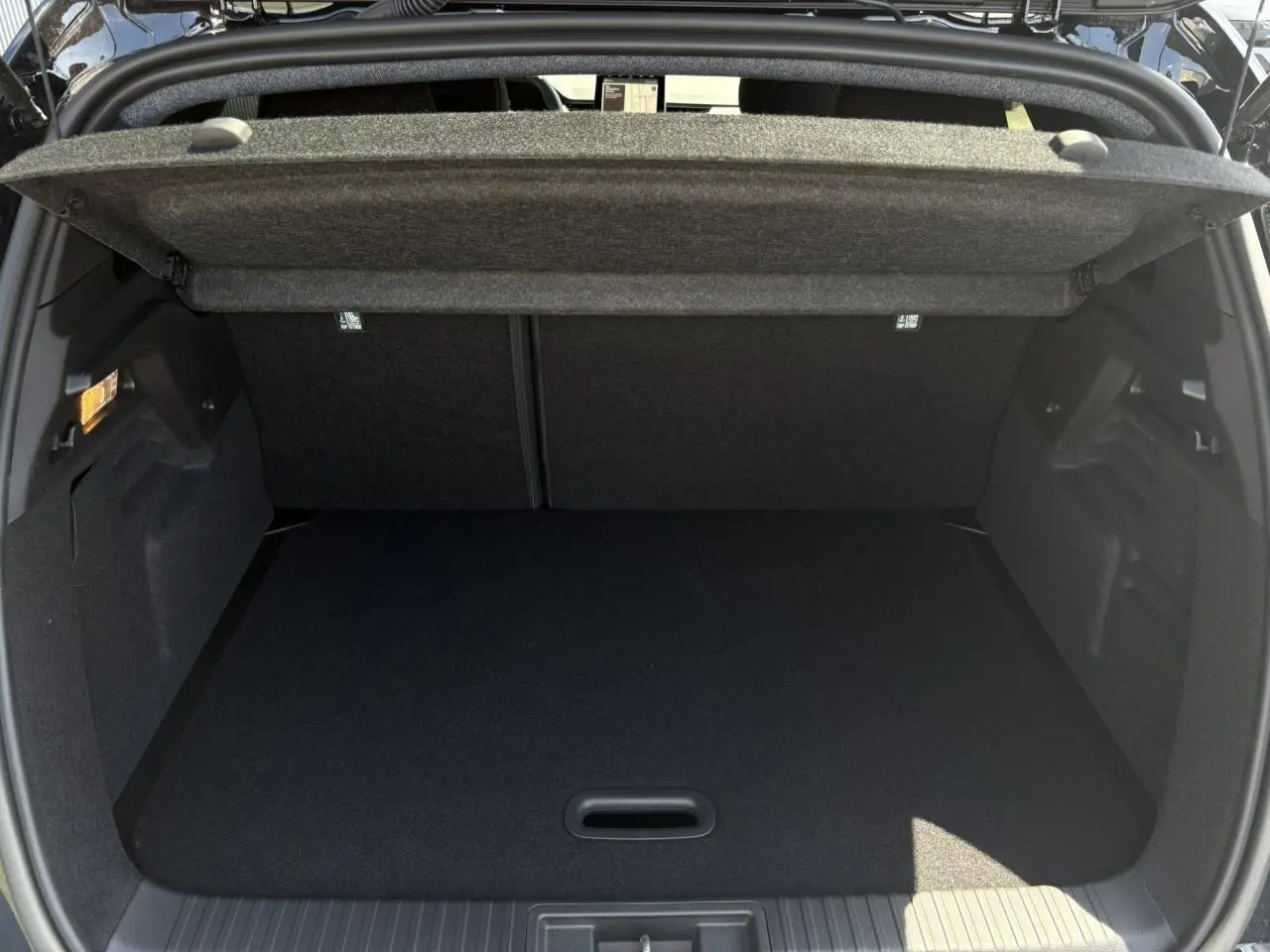 Coffre ouvert vu de l'arrière d'un Renault Captur noir étoile 2025, montrant un espace de rangement propre et spacieux.