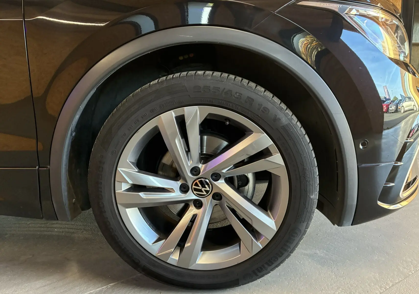 Gros plan sur la roue avant gauche noire d'un Volkswagen Tiguan 2.0 TDI 150 DSG7 R-Line avec jante alu 19 pouces.