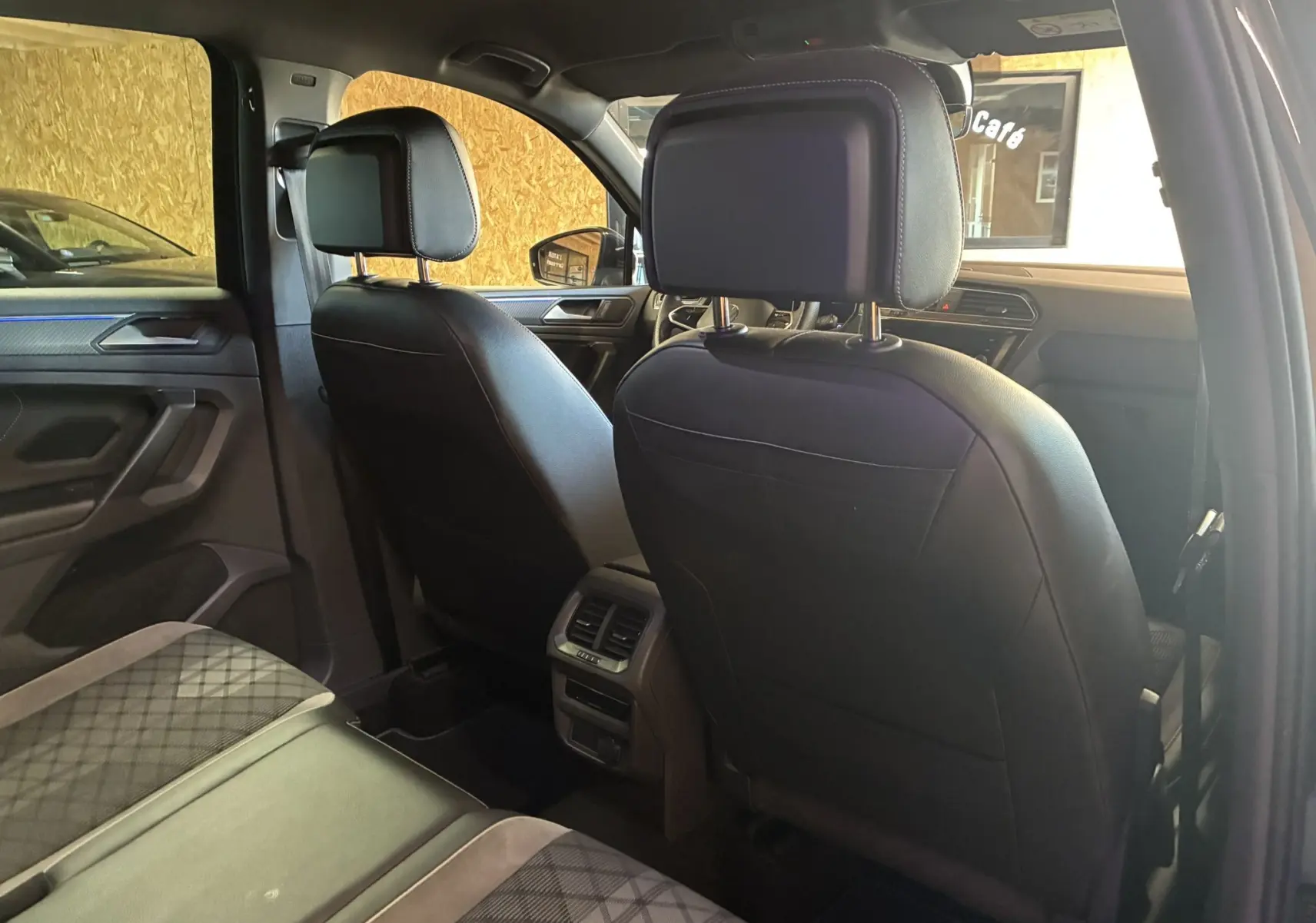 Vue intérieure arrière du Volkswagen Tiguan 2.0 TDI noir, montrant sièges avant en cuir noir et banquette tissu à motifs.
