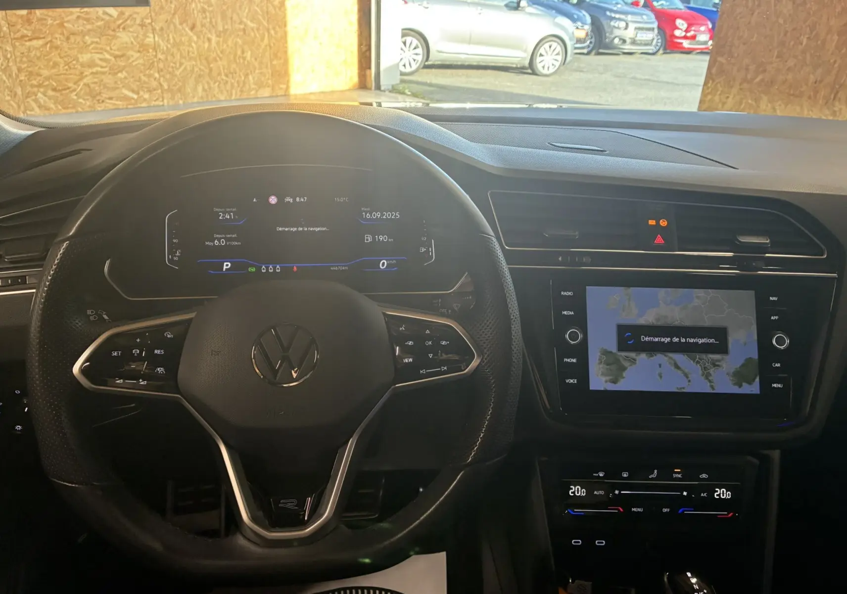 Vue intérieure du tableau de bord du Volkswagen Tiguan noir, avec volant multifonctions et écran tactile de navigation en démarrage.