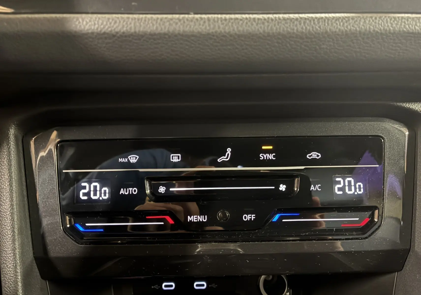 Panneau de contrôle de la climatisation automatique du Volkswagen Tiguan noir, affichant 20°C en mode synchronisé.