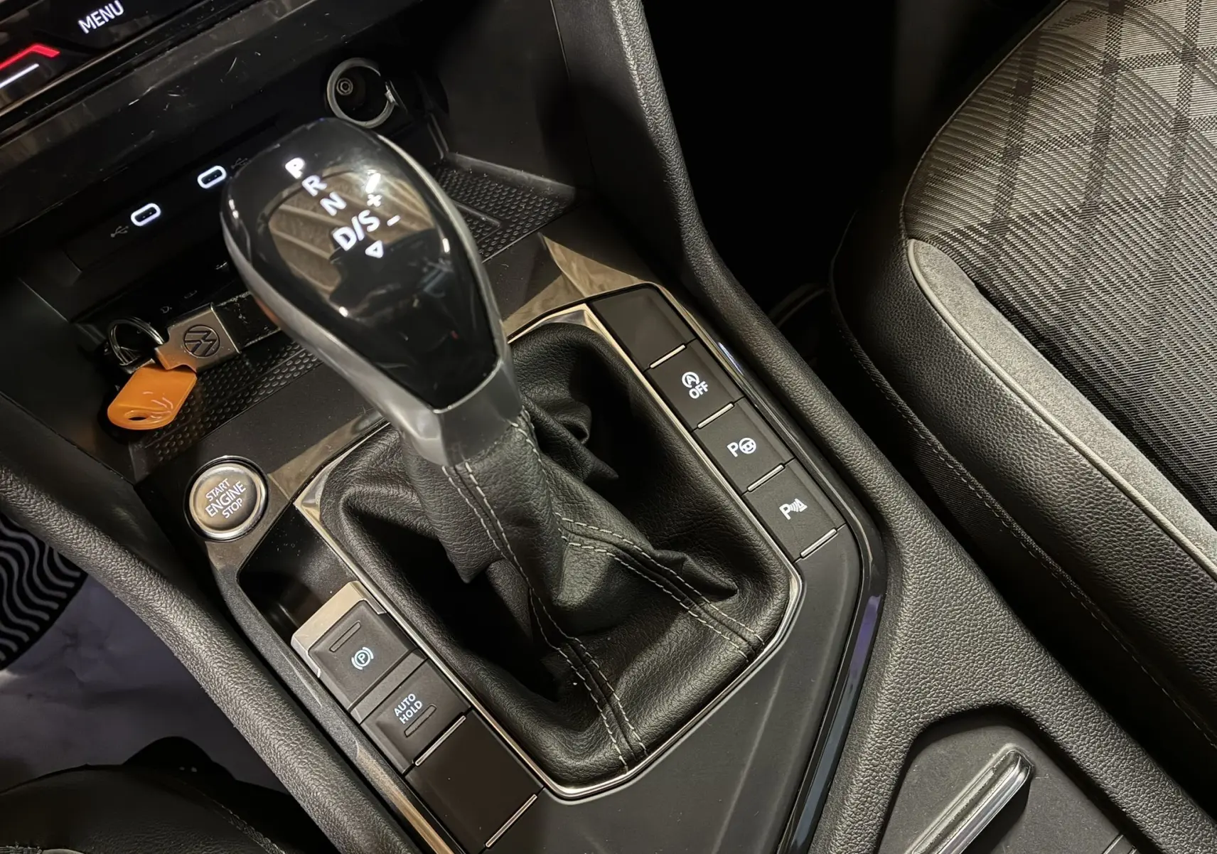 Gros plan sur la console centrale du Volkswagen Tiguan noir, mettant en valeur le levier de vitesse automatique et les commandes d'assistance.