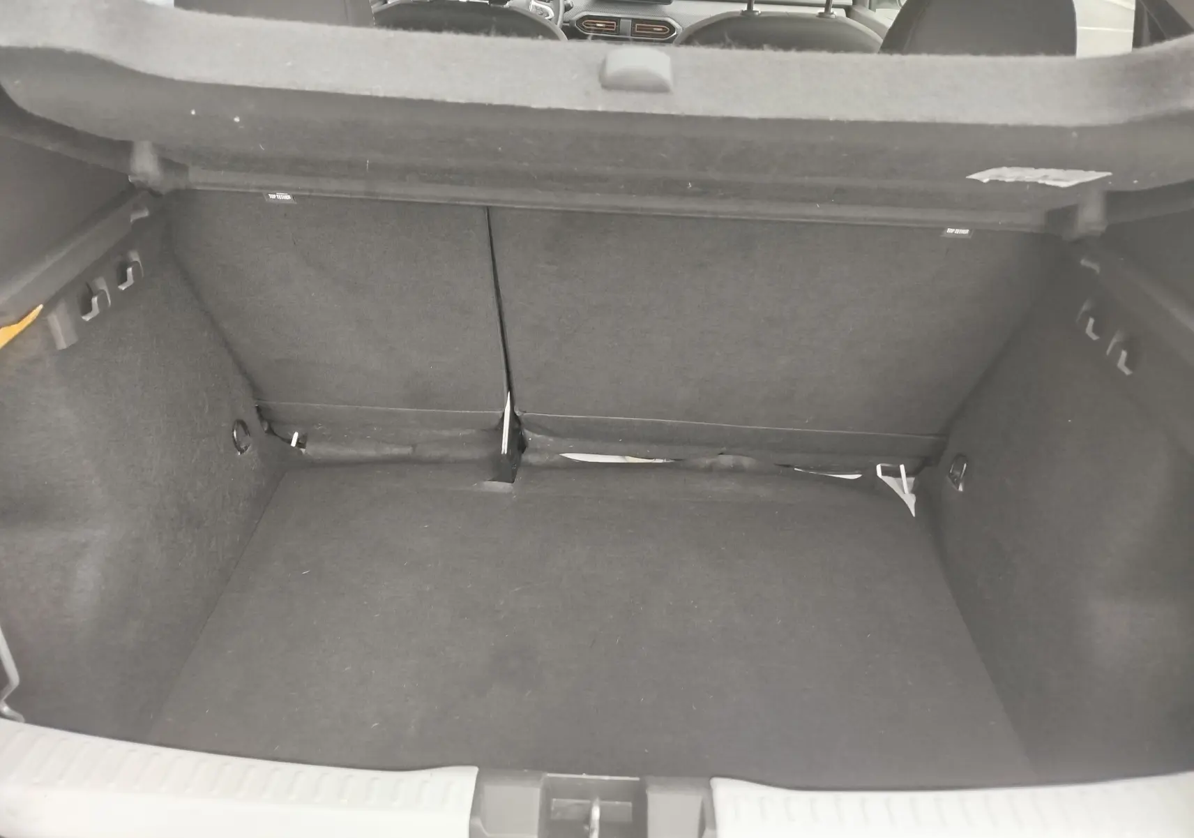 Coffre ouvert de la Dacia Sandero Stepway blanc glacier, vue intérieure arrière montrant l'espace de chargement vide.