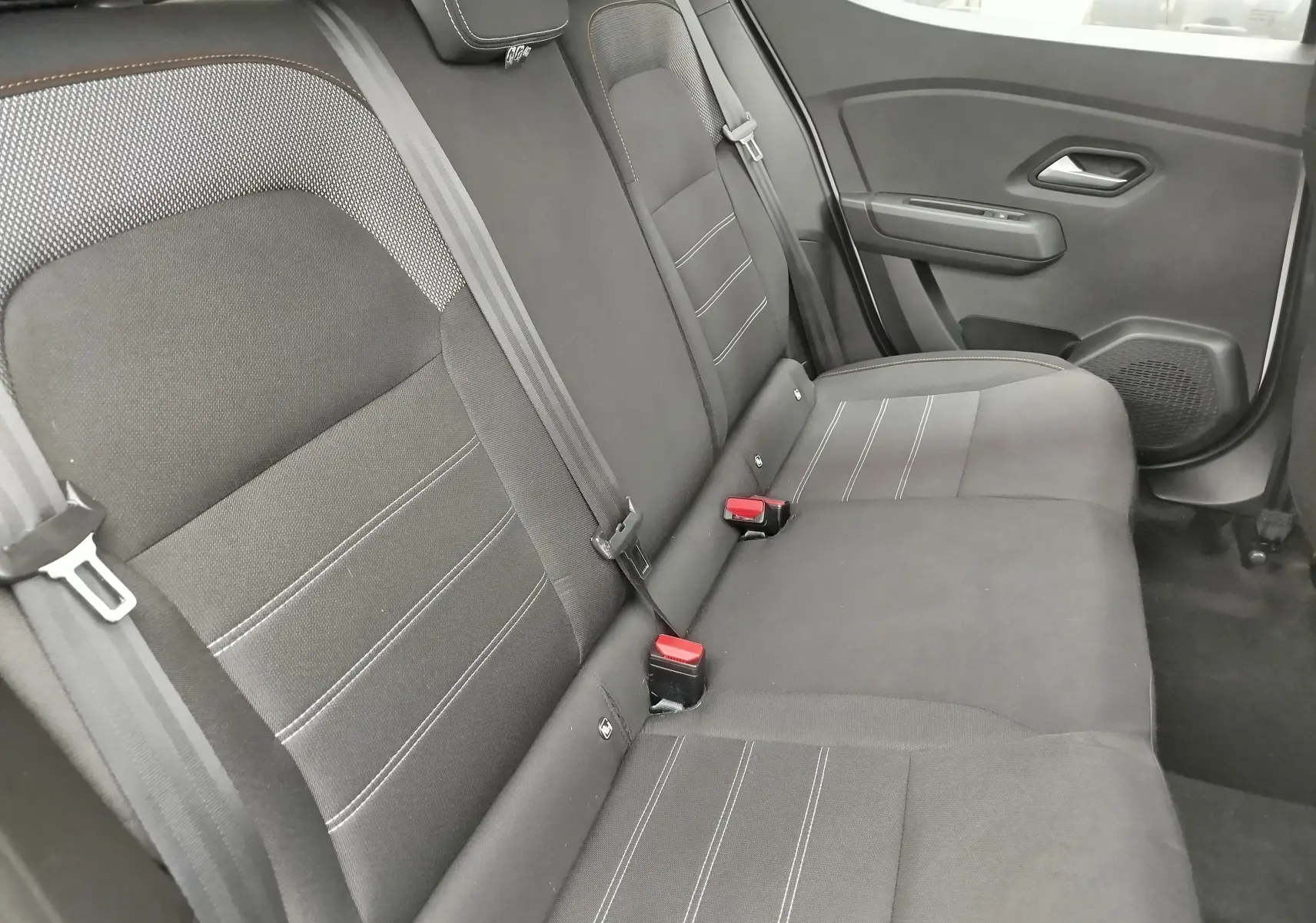 Vue latérale droite de la banquette arrière en tissu gris foncé de la Dacia Sandero Stepway 2021 blanc glacier.