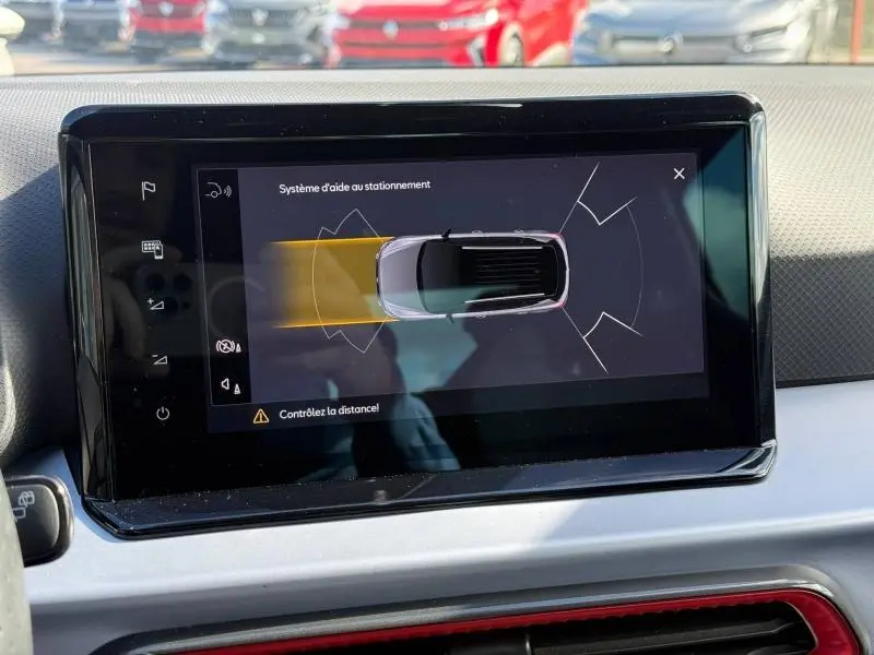 Écran central montrant l’aide au stationnement du SEAT Arona 2025, vue du dessus du véhicule avec toit noir et carrosserie rouge.