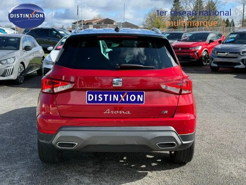 Vue arrière d'un SEAT Arona 2025 rouge Désir avec toit noir, version FR, sur un parking extérieur.