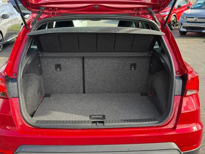 Coffre ouvert vu de l'arrière d'un SEAT Arona 2025 Rouge Désir avec toit noir, montrant l'espace de chargement vide.