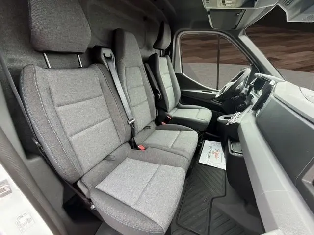 Vue intérieure côté droit du Renault Master blanc 2025, montrant les sièges avant en tissu gris et le tableau de bord moderne.