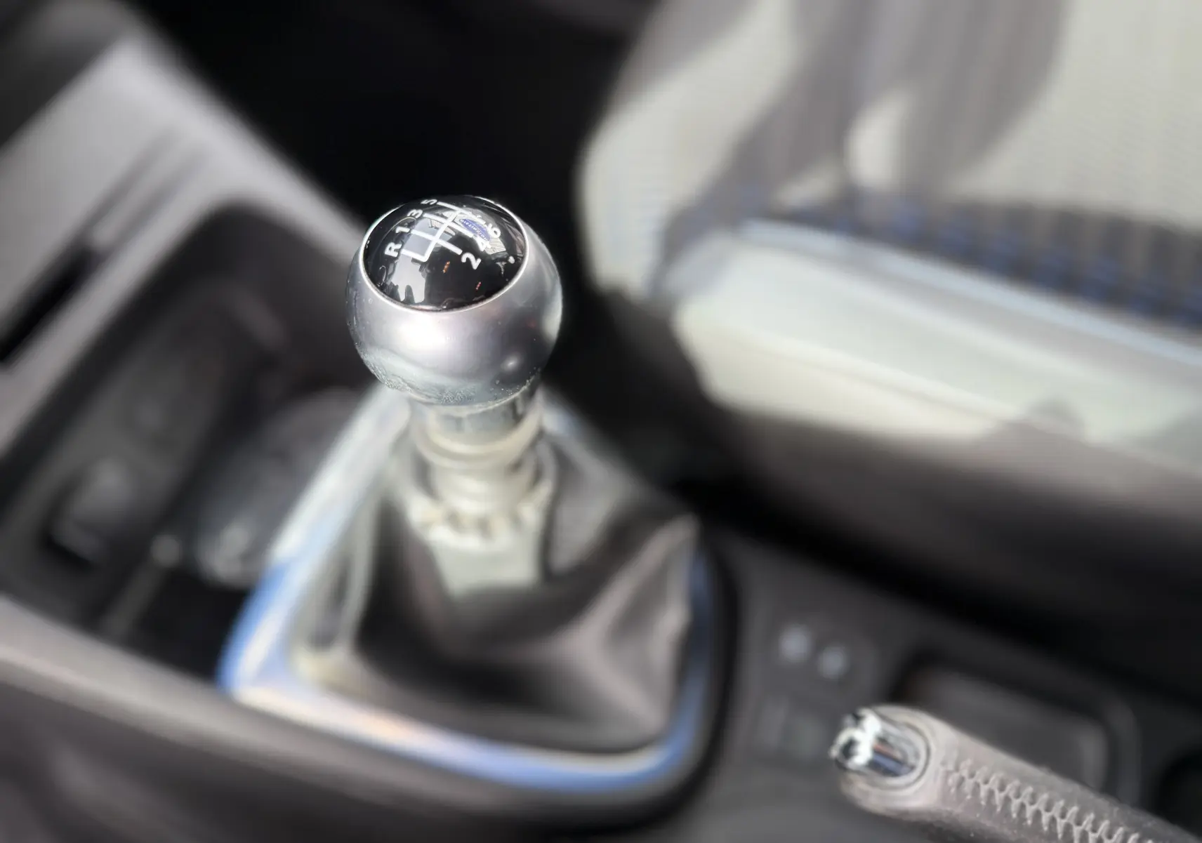 Gros plan sur le levier de vitesses manuel du Renault Captur blanc 2017, intérieur avec siège clair en arrière-plan.