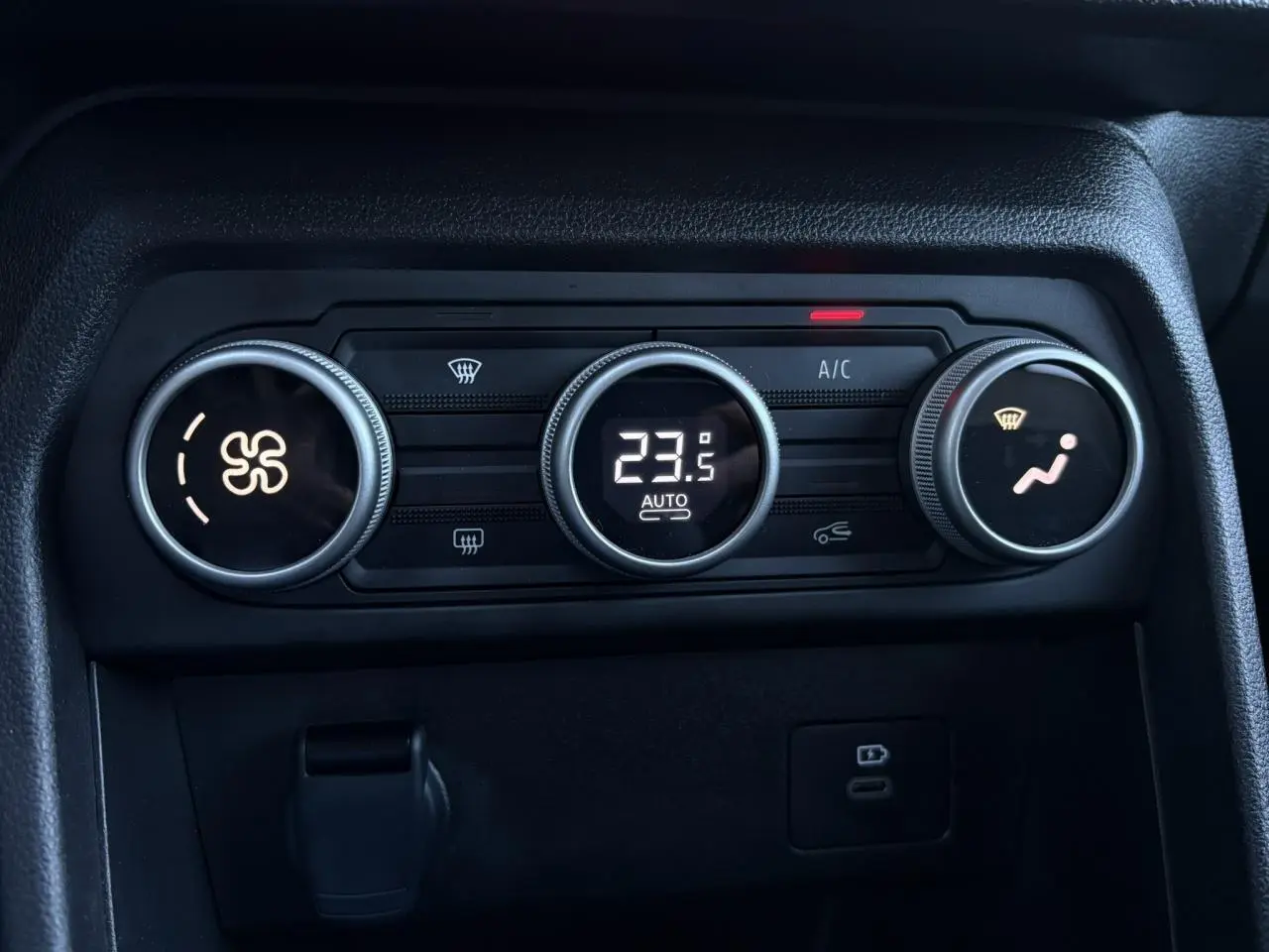 Gros plan sur les commandes de climatisation automatique du Dacia Jogger gris, affichant 23,5°C avec réglages ventilateur et air dirigé.