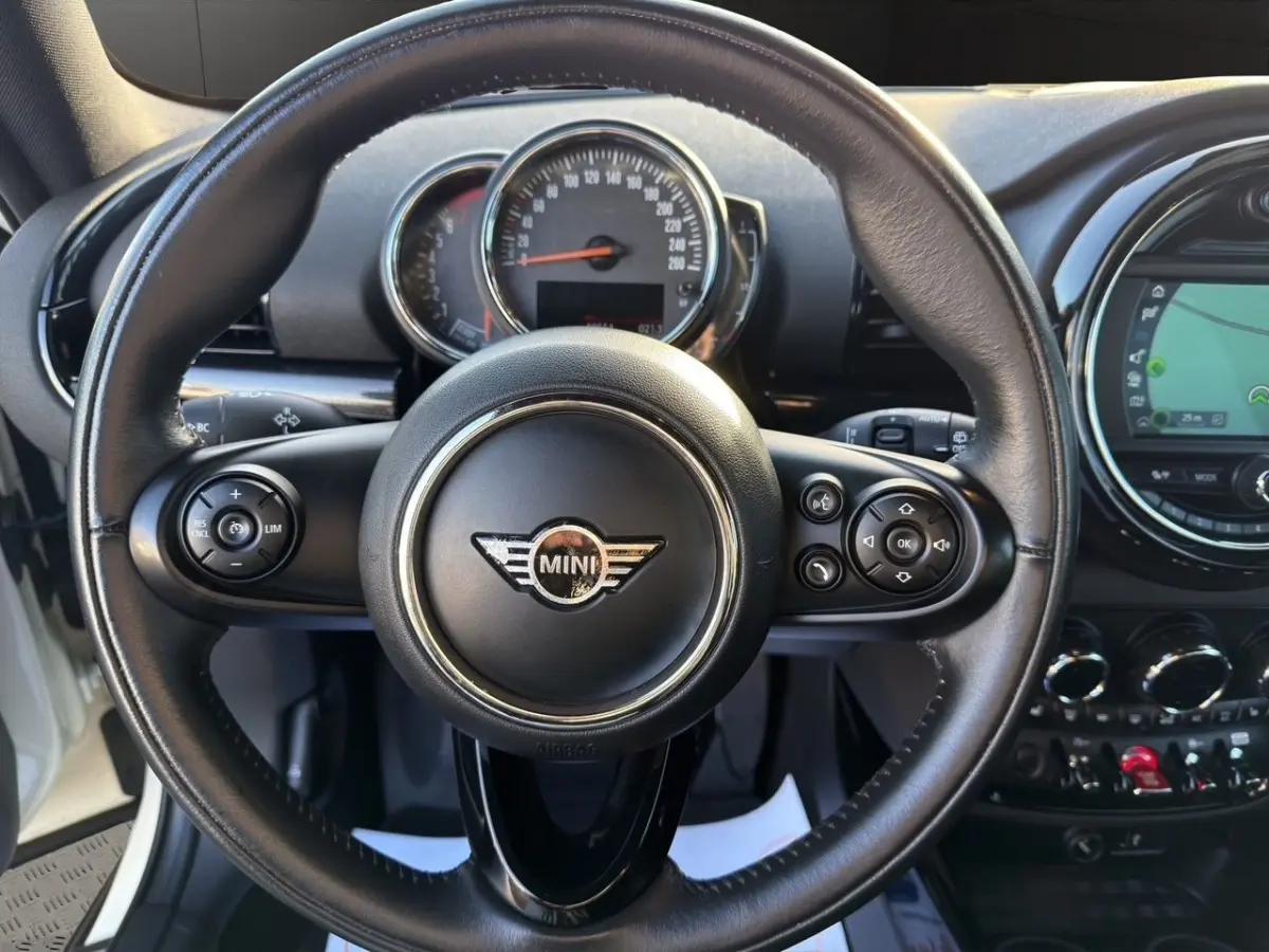 Vue centrée sur le volant cuir noir de la MINI Clubman F54 avec tableau de bord et écran tactile en arrière-plan.