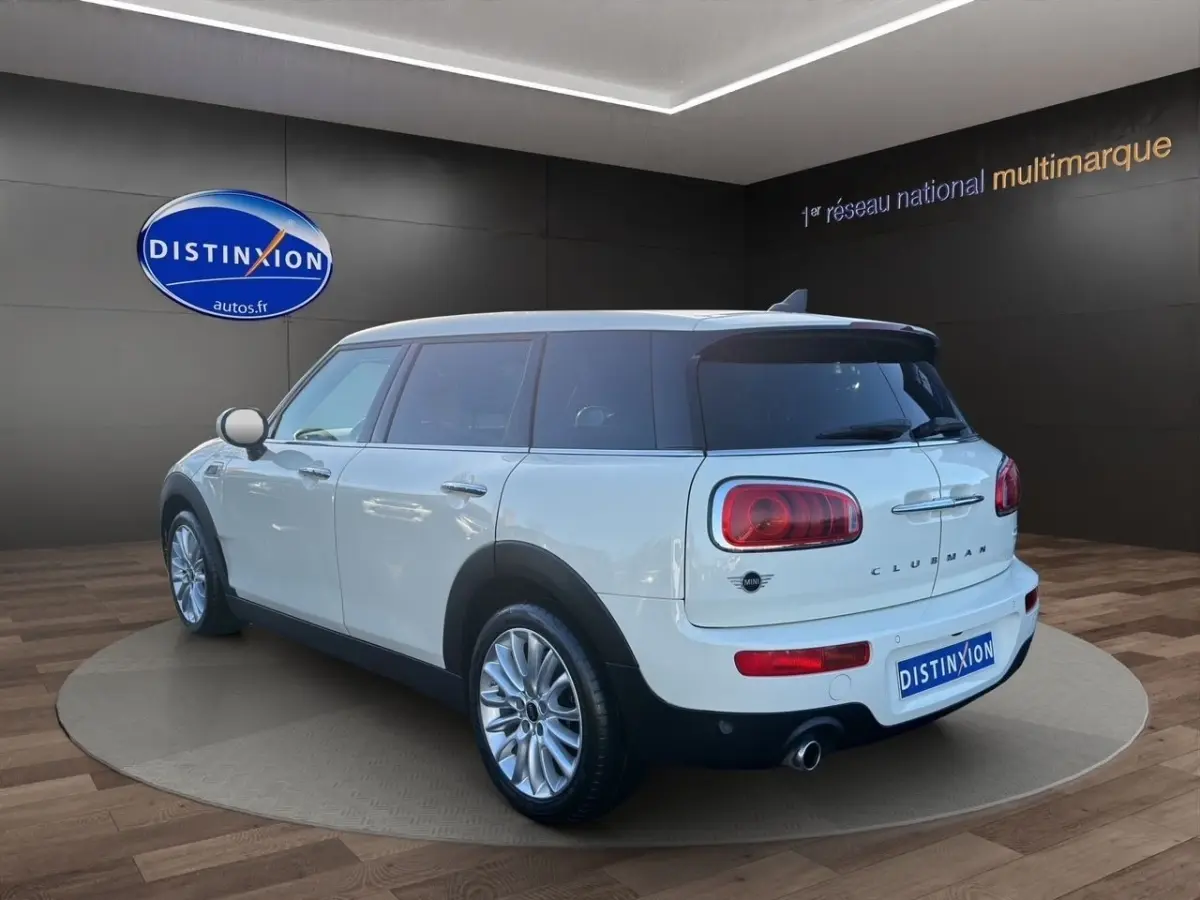 Vue 3/4 arrière droite d'une MINI Clubman blanche avec toit noir, feux arrière caractéristiques et jantes alliage.