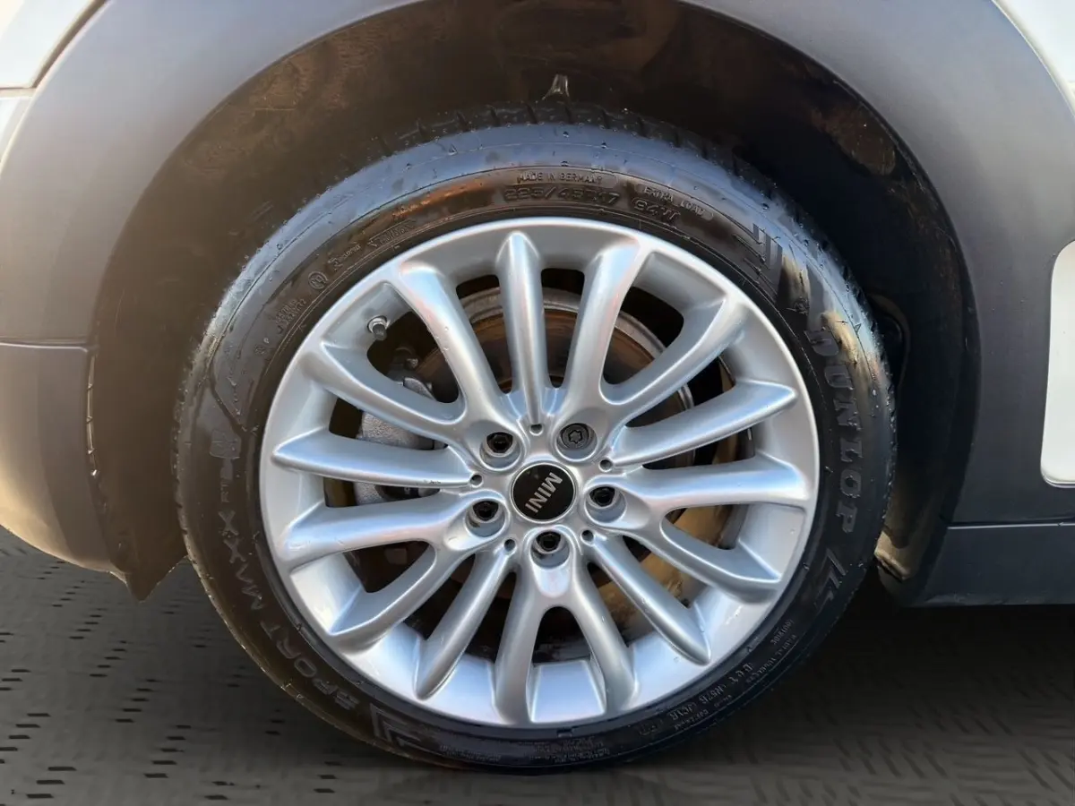 Gros plan sur la jante alliage argentée de la roue avant droite d'une MINI Clubman blanche, avec pneu Dunlop.