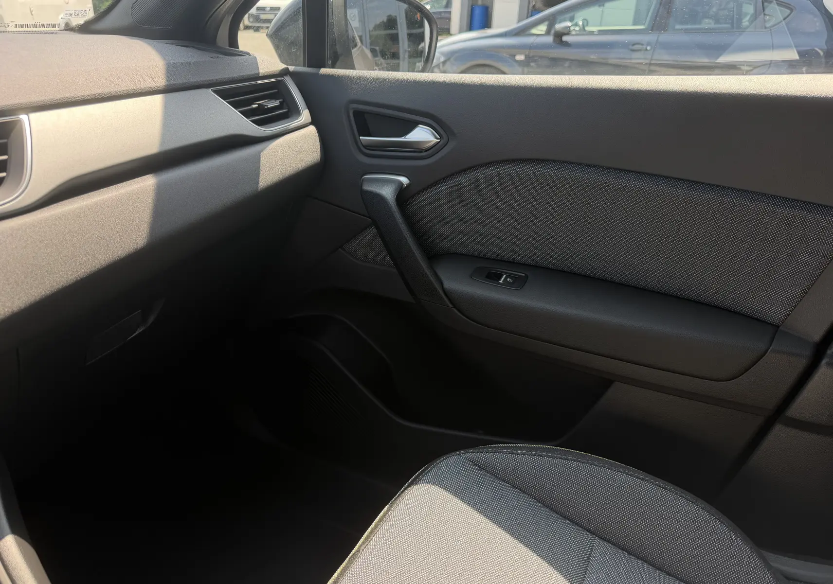 Vue intérieure côté passager du Renault Captur 2026, montrant la porte et le siège en tissu gris.