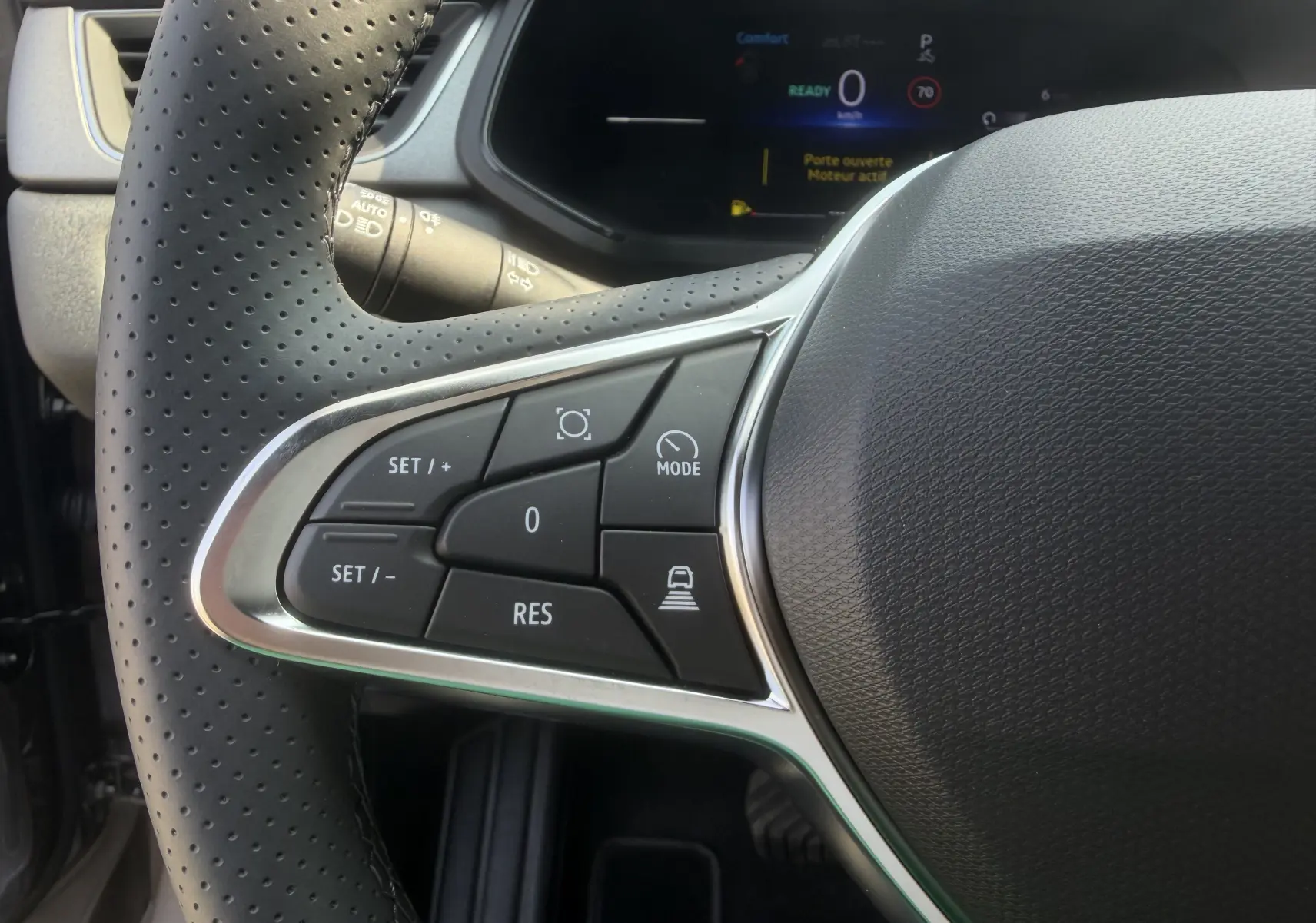 Gros plan sur les commandes gauche du volant textile perforé du Renault Captur 1.8 E-Tech hybride 2026.