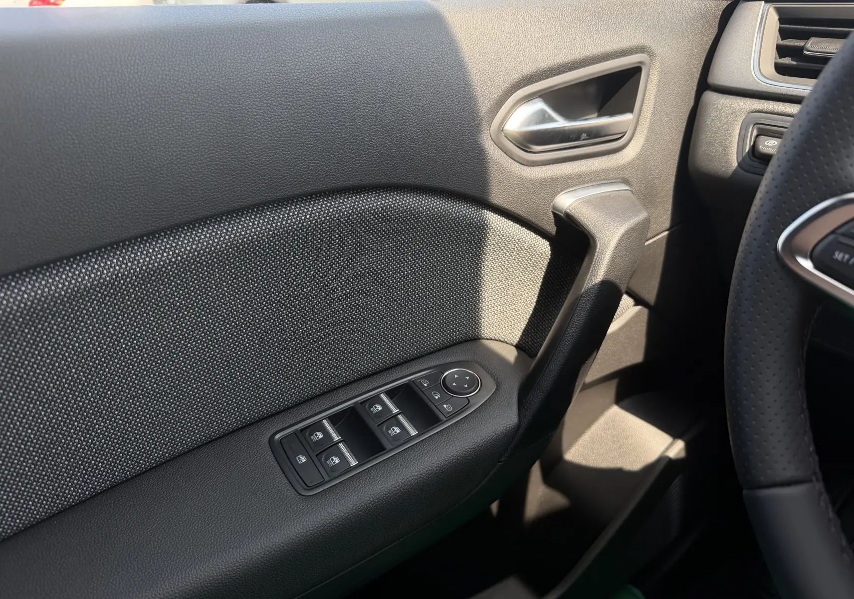 Détail de la porte côté gauche du Renault Captur 2026, avec commandes de vitres et poignée noire texturée.