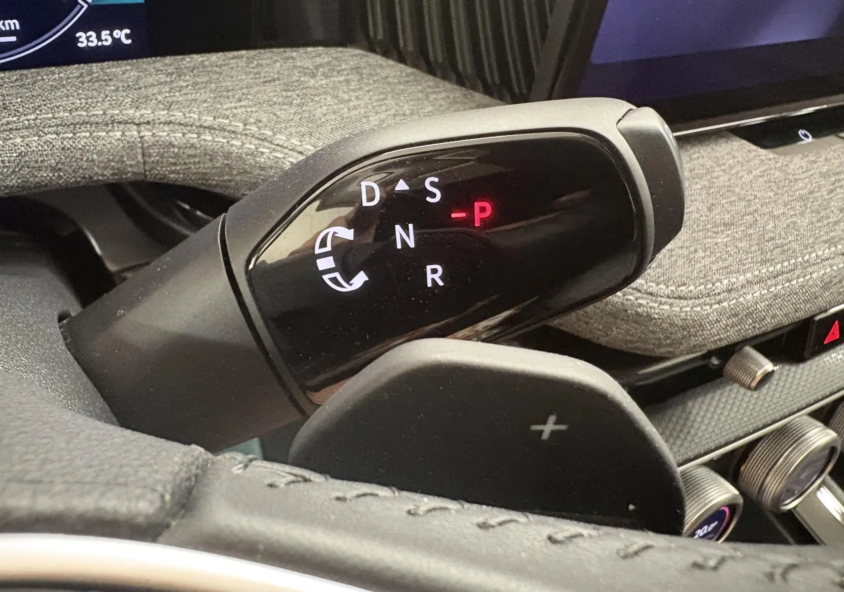 Gros plan sur le sélecteur de vitesses noir brillant dans l'habitacle du Skoda Superb Combi 2025, avec tableau de bord textile gris.
