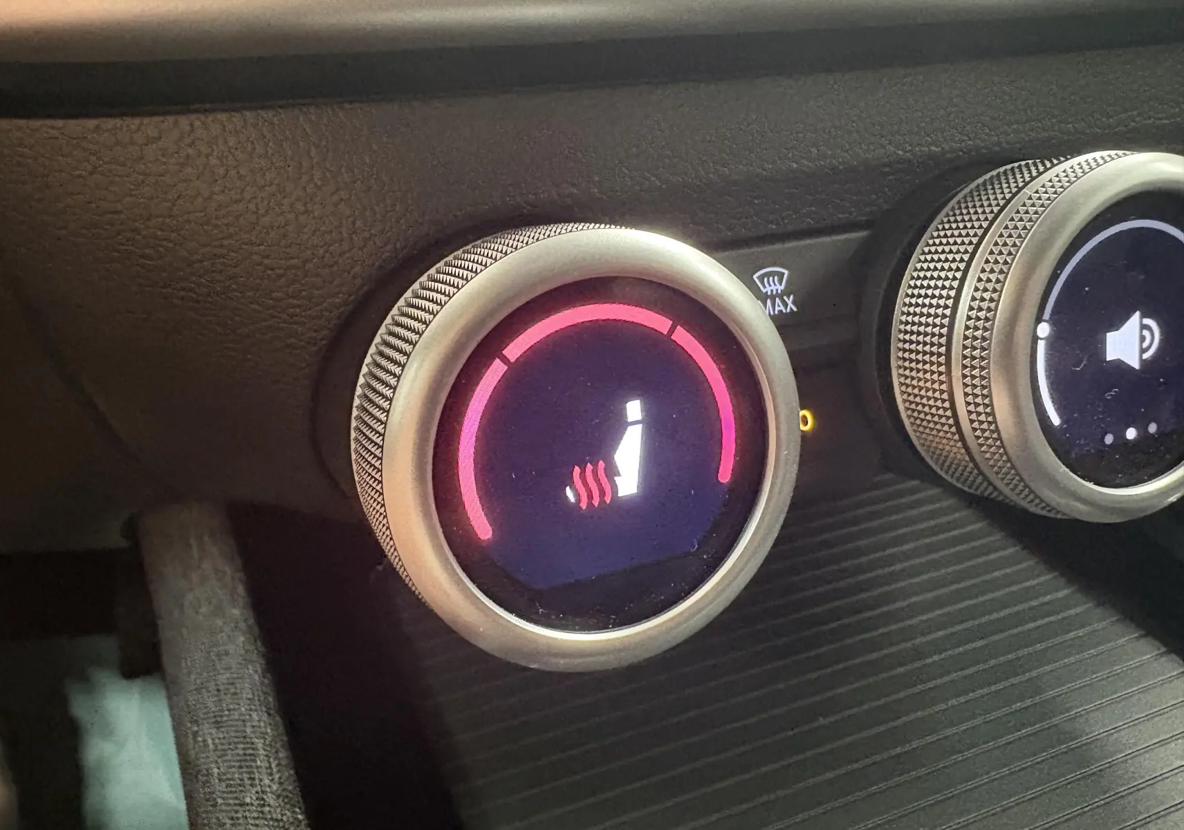 Gros plan sur le bouton de réglage du siège chauffant avec molette argentée dans l'habitacle du Skoda Superb Combi gris argent.