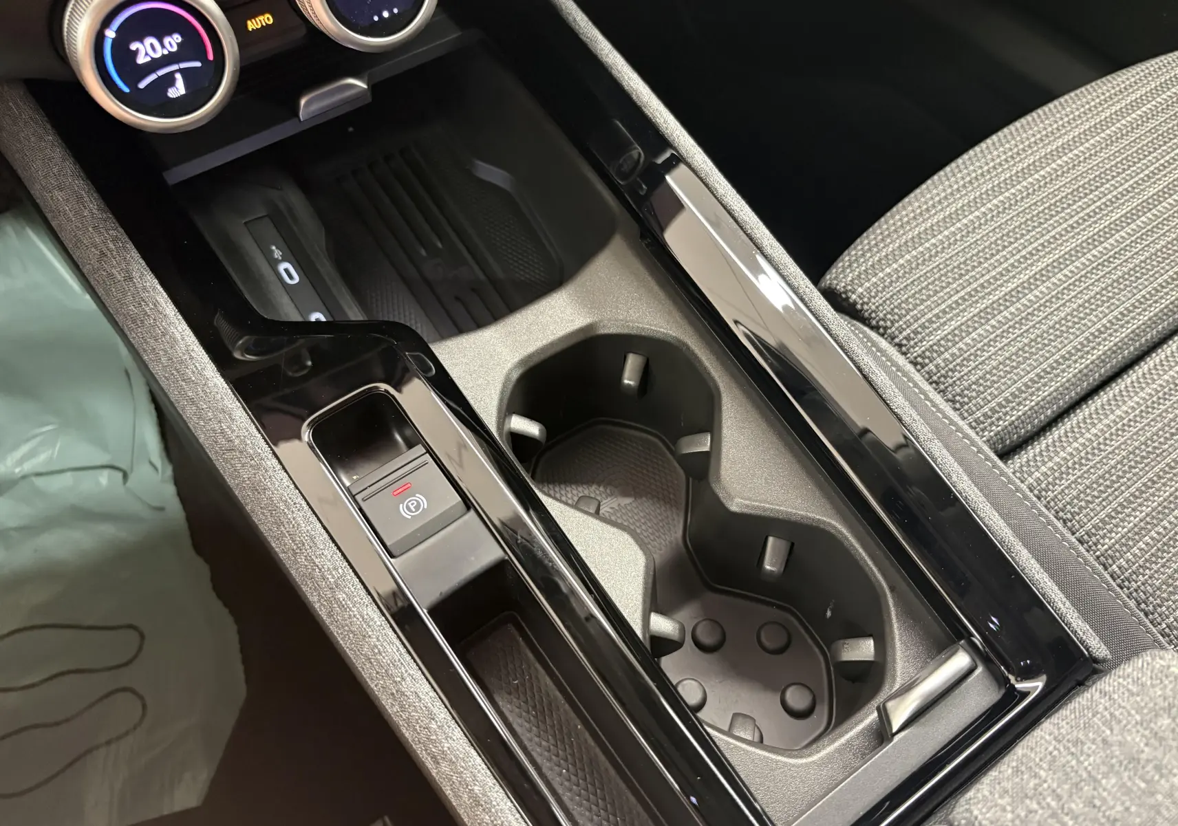 Gros plan sur la console centrale intérieure de la Skoda Superb Combi 2025, avec porte-gobelets et bouton frein à main électrique.