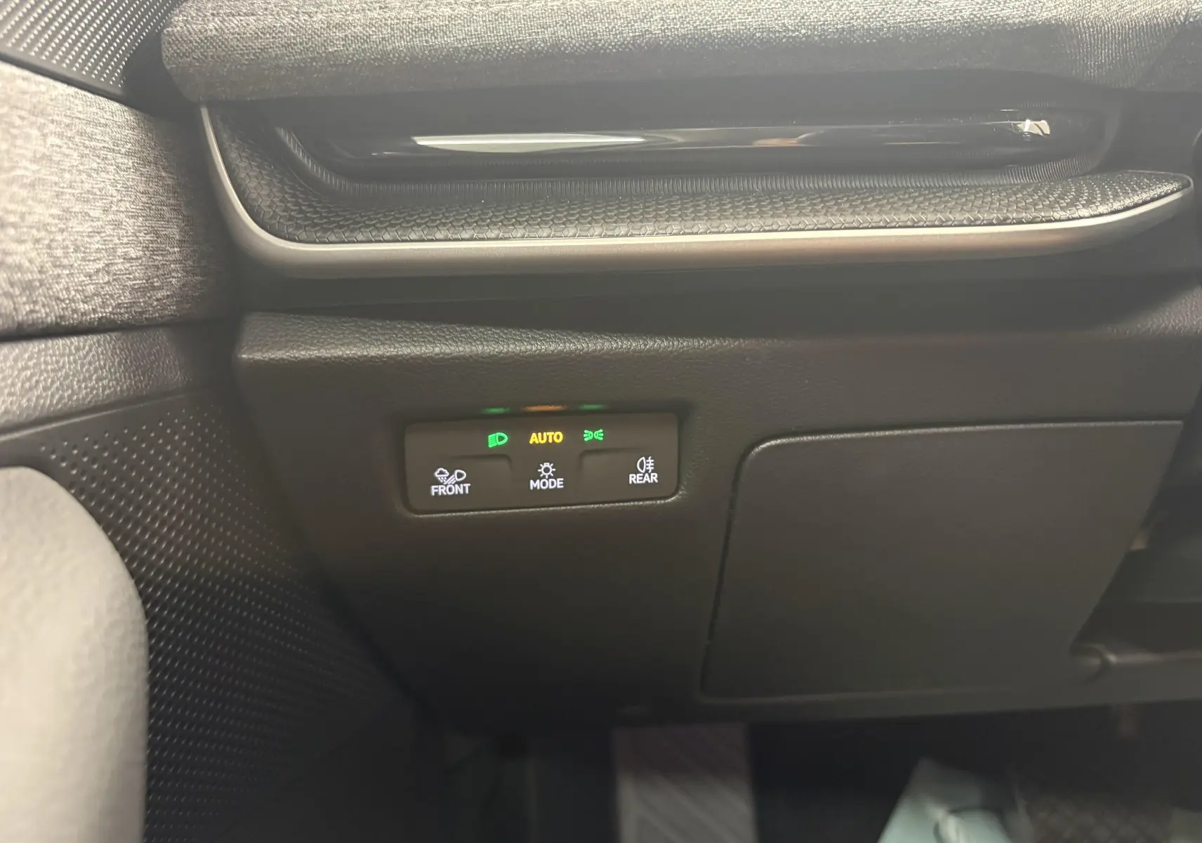 Détail du panneau de commande des feux à gauche du volant dans une Skoda Superb Combi gris argent 2025.