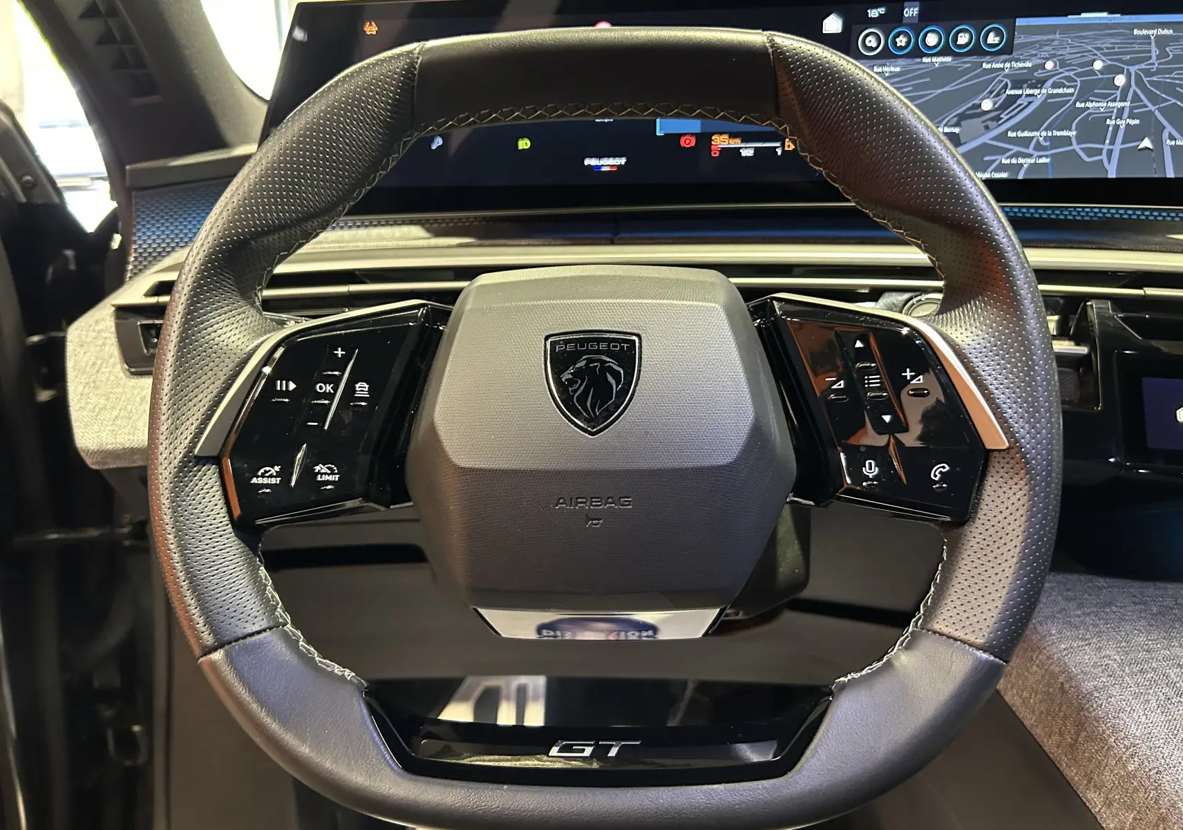 Vue rapprochée du volant cuir perforé noir avec logo Peugeot et inscription GT du SUV 5008 hybride 2025.