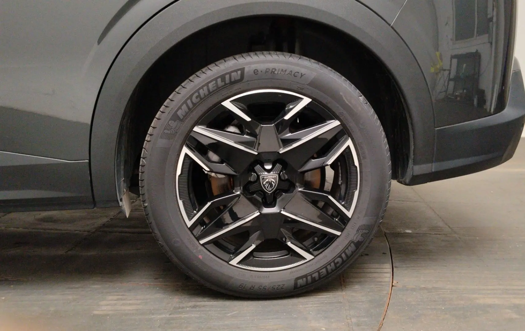 Gros plan sur l’avant droit du Peugeot 5008 gris titane, mettant en valeur le phare LED et la jante noire à inserts métallisés.