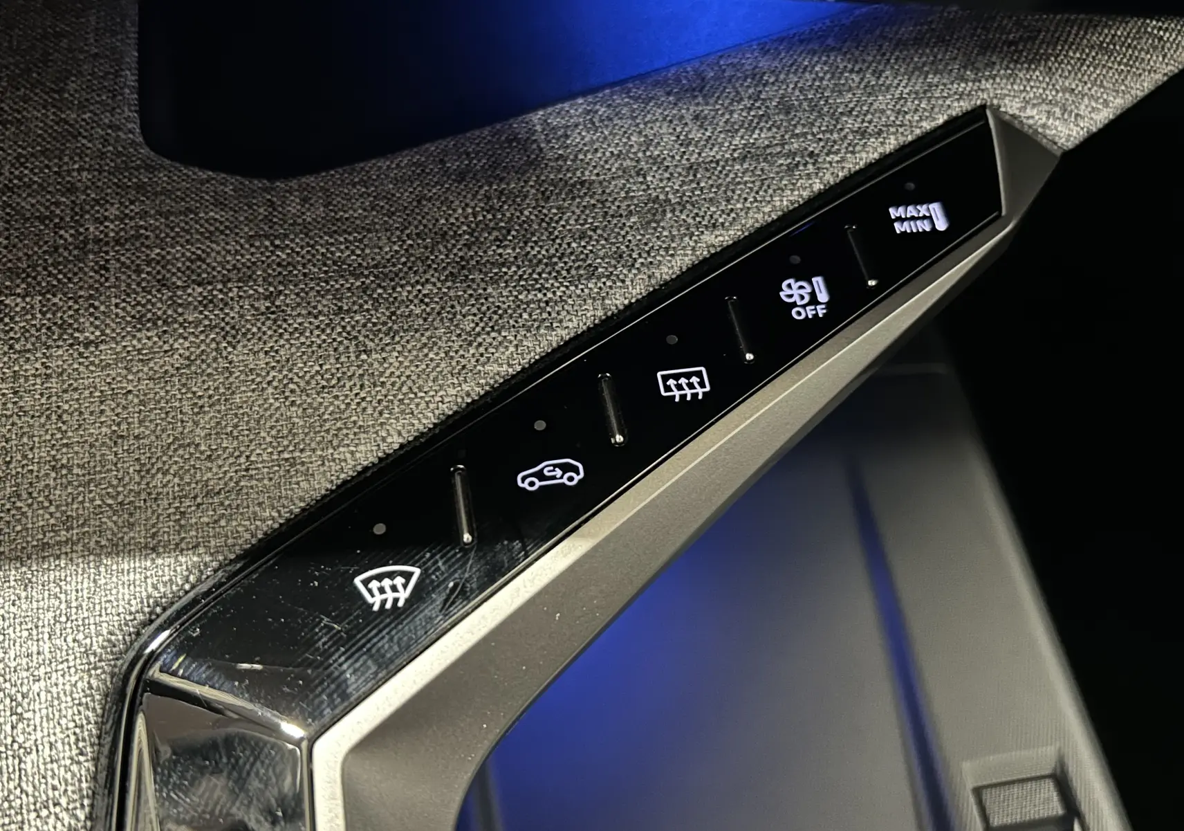 Gros plan sur les commandes de climatisation avec éclairage blanc, sur la console intérieure du Peugeot 5008 gris Titane.
