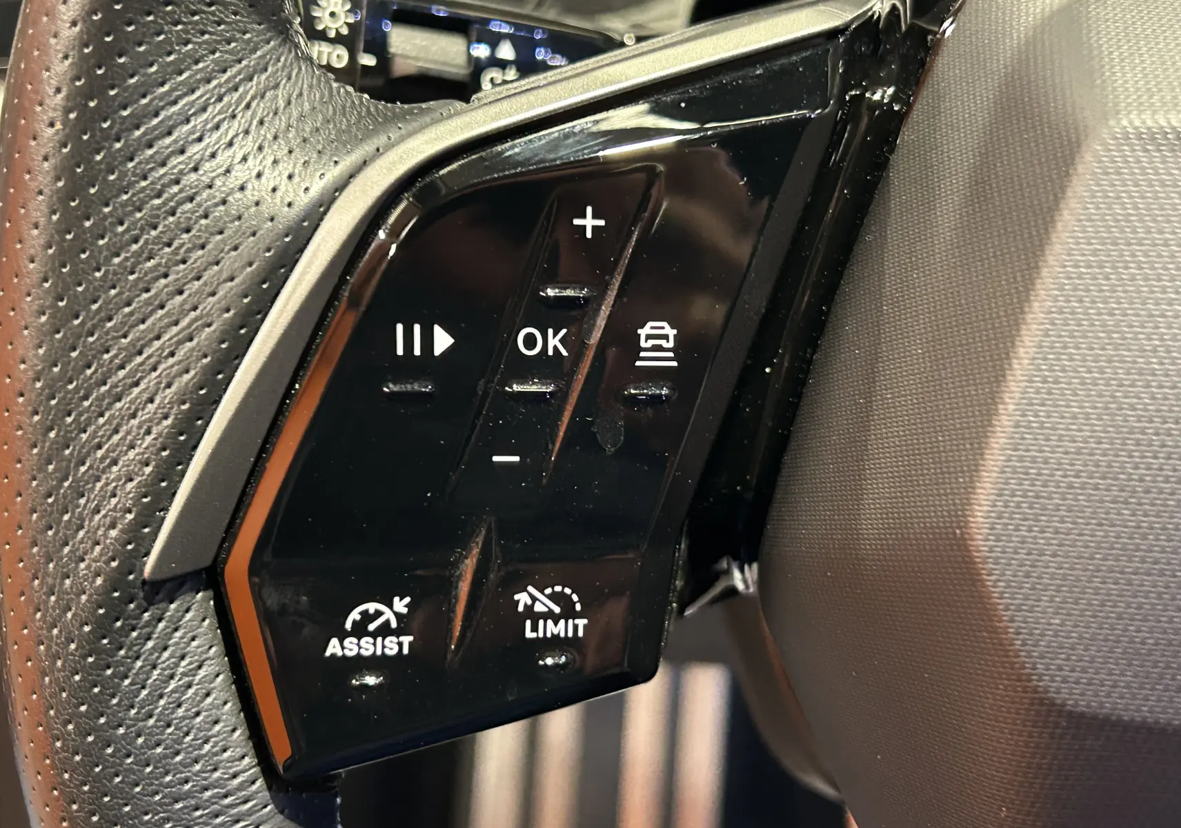 Gros plan sur les commandes noires du volant côté gauche du Peugeot 5008 gris Titane, version hybride 2025.