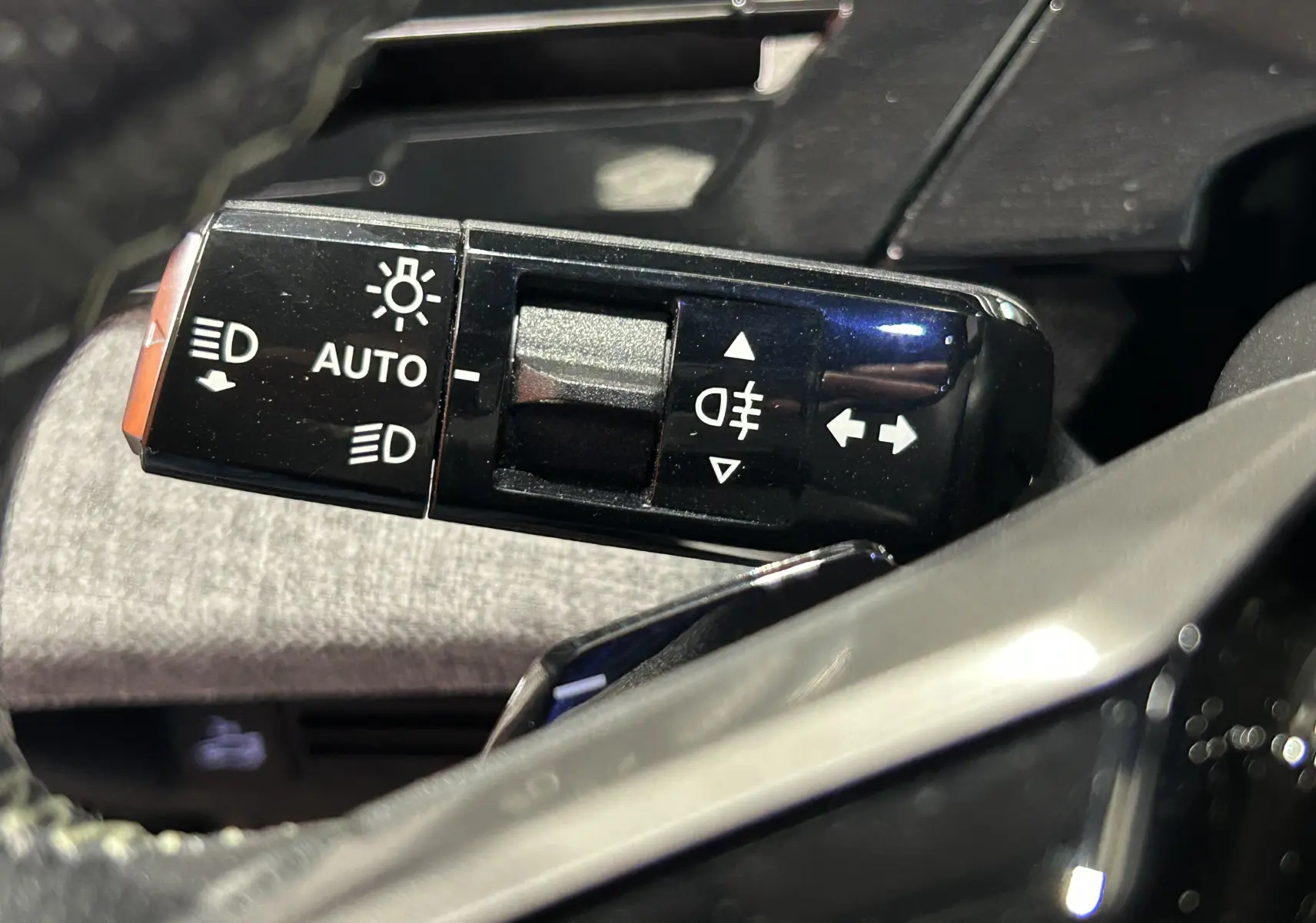 Gros plan sur la commande des feux et clignotants du Peugeot 5008 III Hybrid gris titane, intérieur côté gauche.