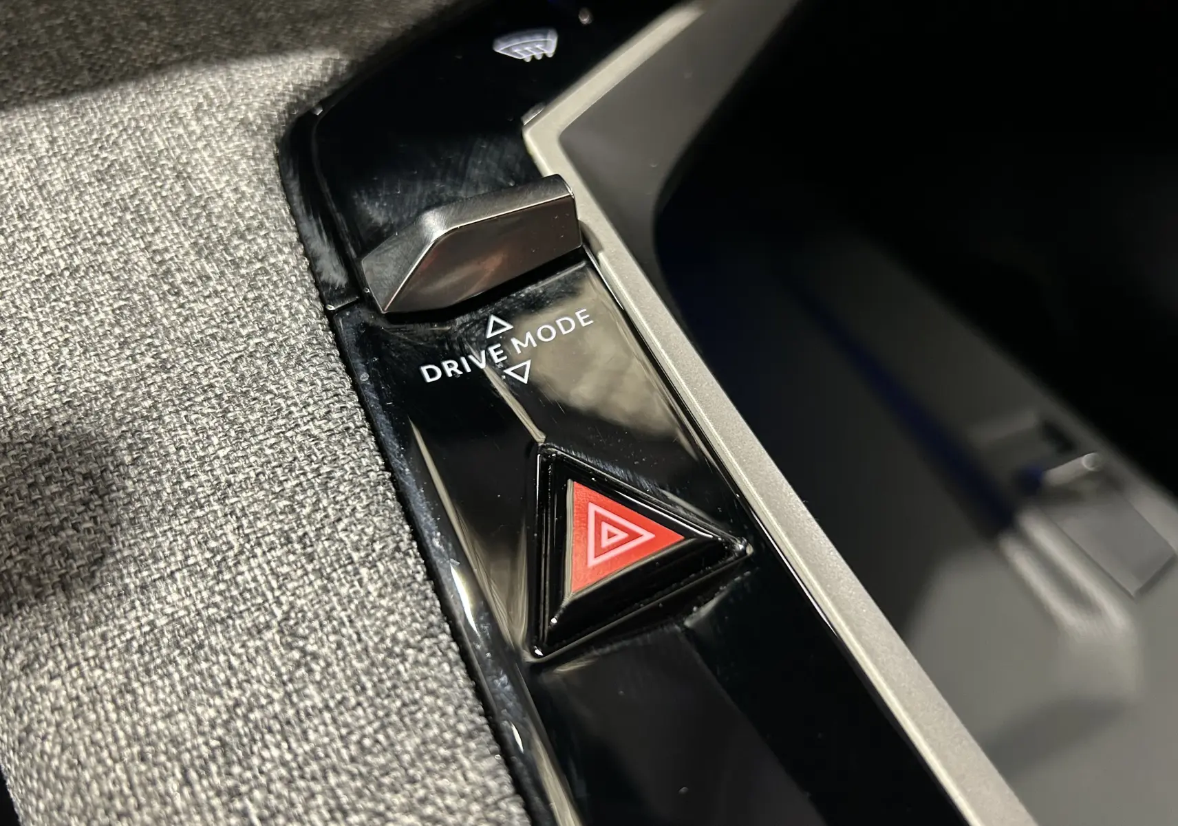 Gros plan sur la console centrale du Peugeot 5008 III Hybrid 145, bouton triangle rouge d’alerte et sélecteur Drive Mode.