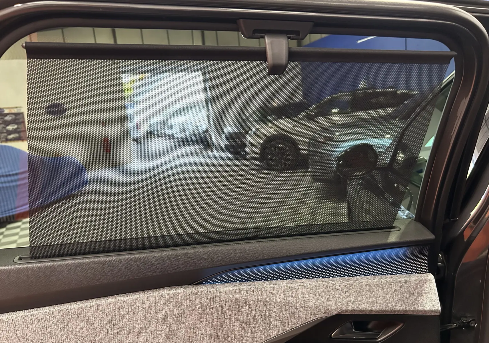 Vue intérieure du côté gauche de la porte arrière du Peugeot 5008 gris Titane avec pare-soleil en filet déployé.
