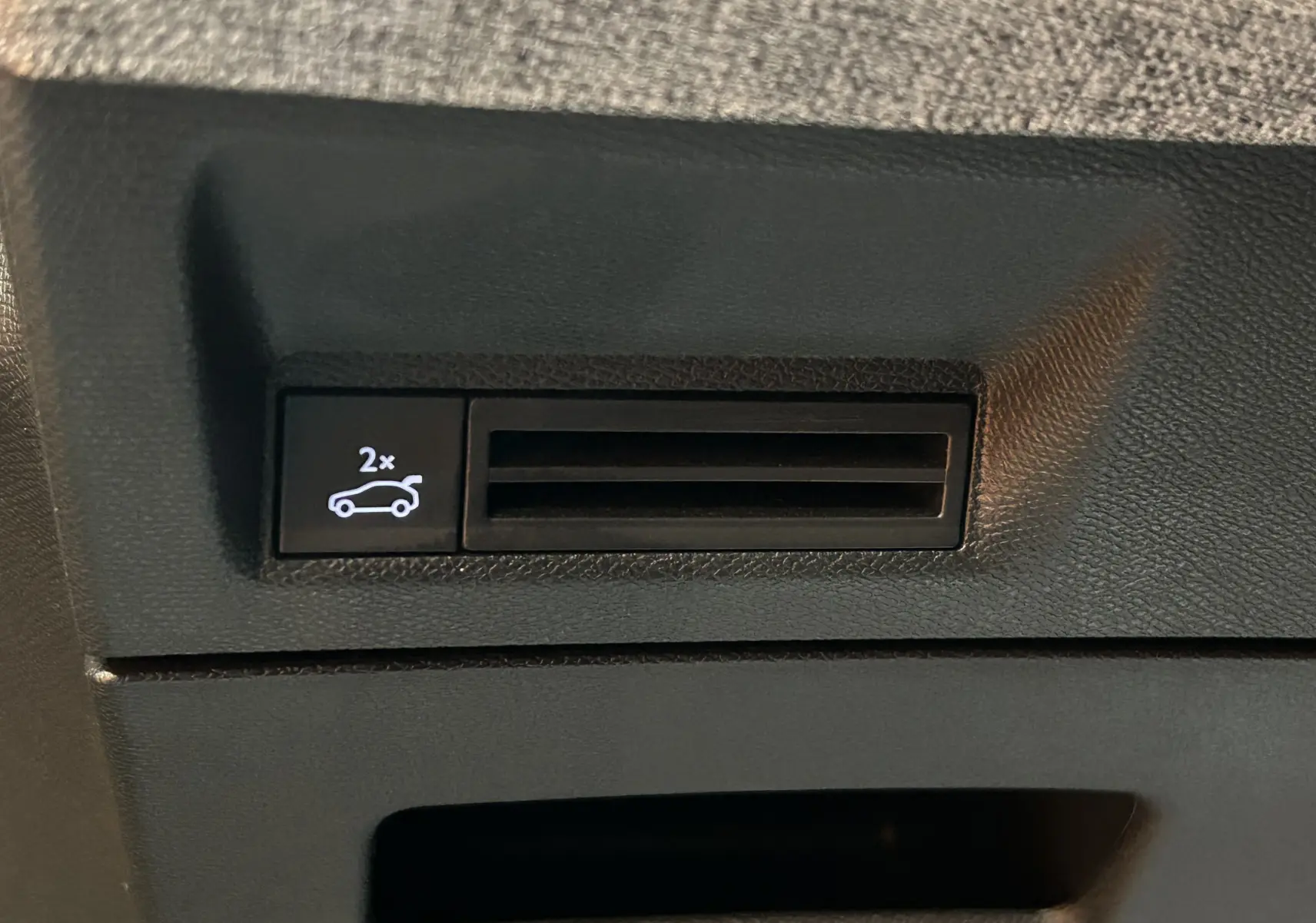 Gros plan sur le bouton d'ouverture électrique du hayon dans l'habitacle du Peugeot 5008 gris titane.