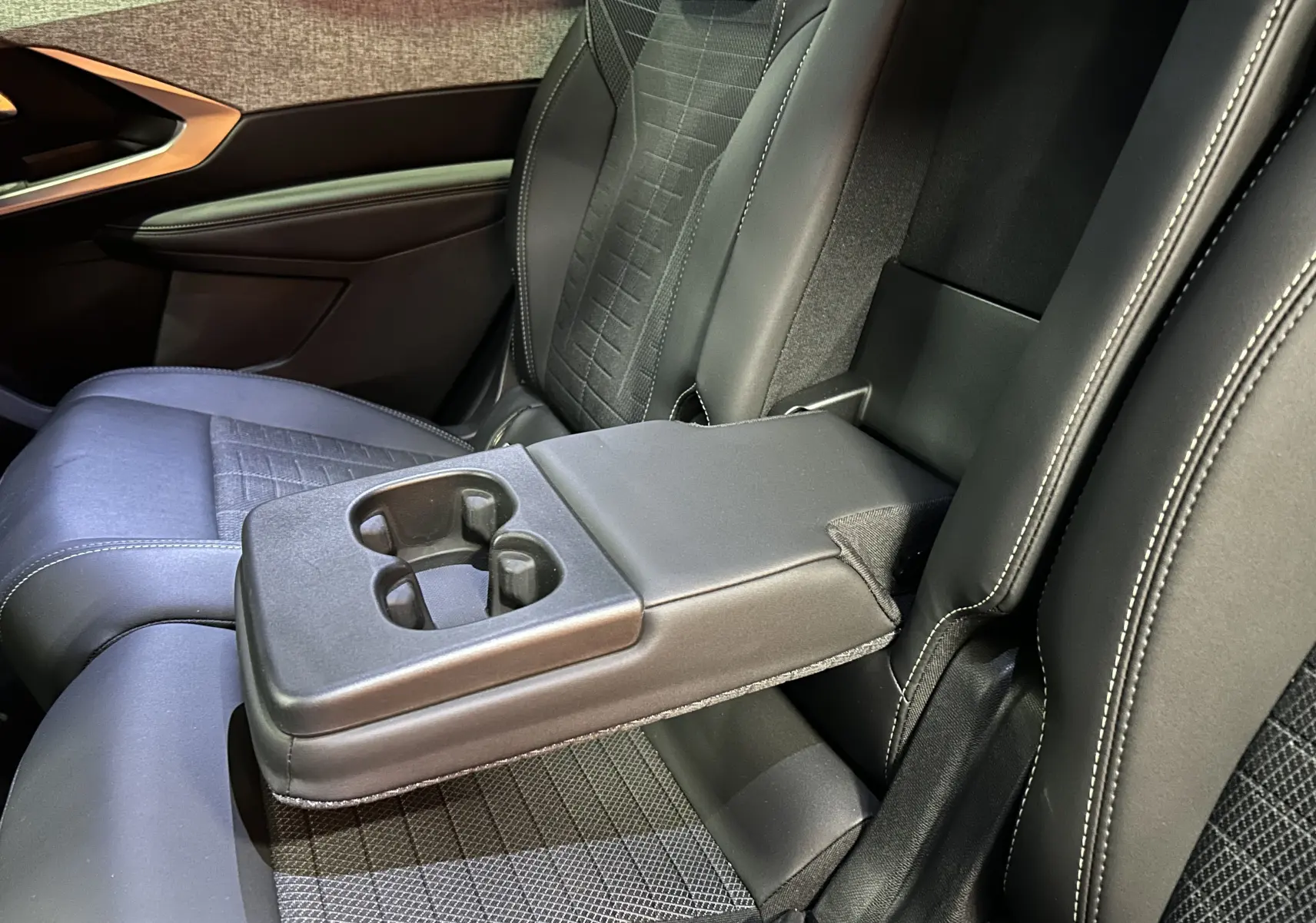 Vue rapprochée de l'accoudoir central arrière avec porte-gobelets dans le siège arrière noir du Peugeot 5008 gris Titane.