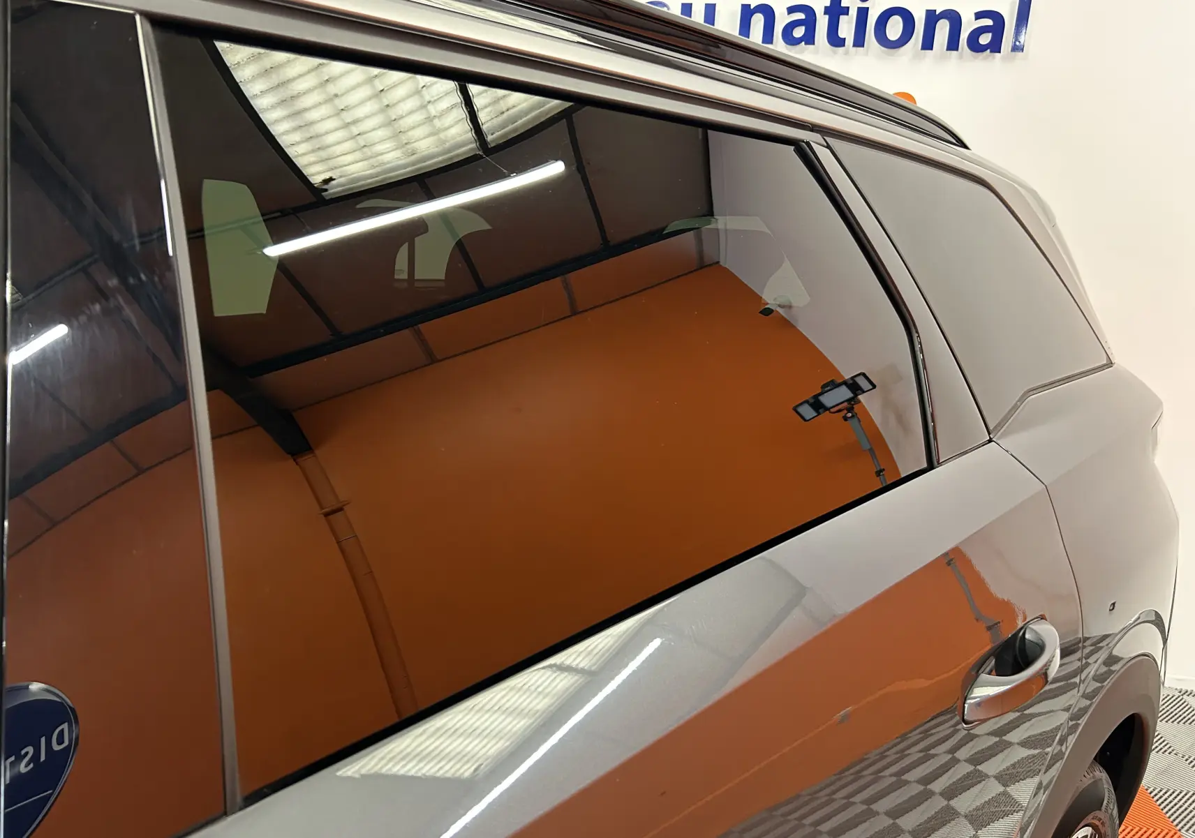 Détail du côté droit arrière gris titane du Peugeot 5008 III Hybrid 145 e-DCS6 GT avec vitre teintée et poignée de porte visible.