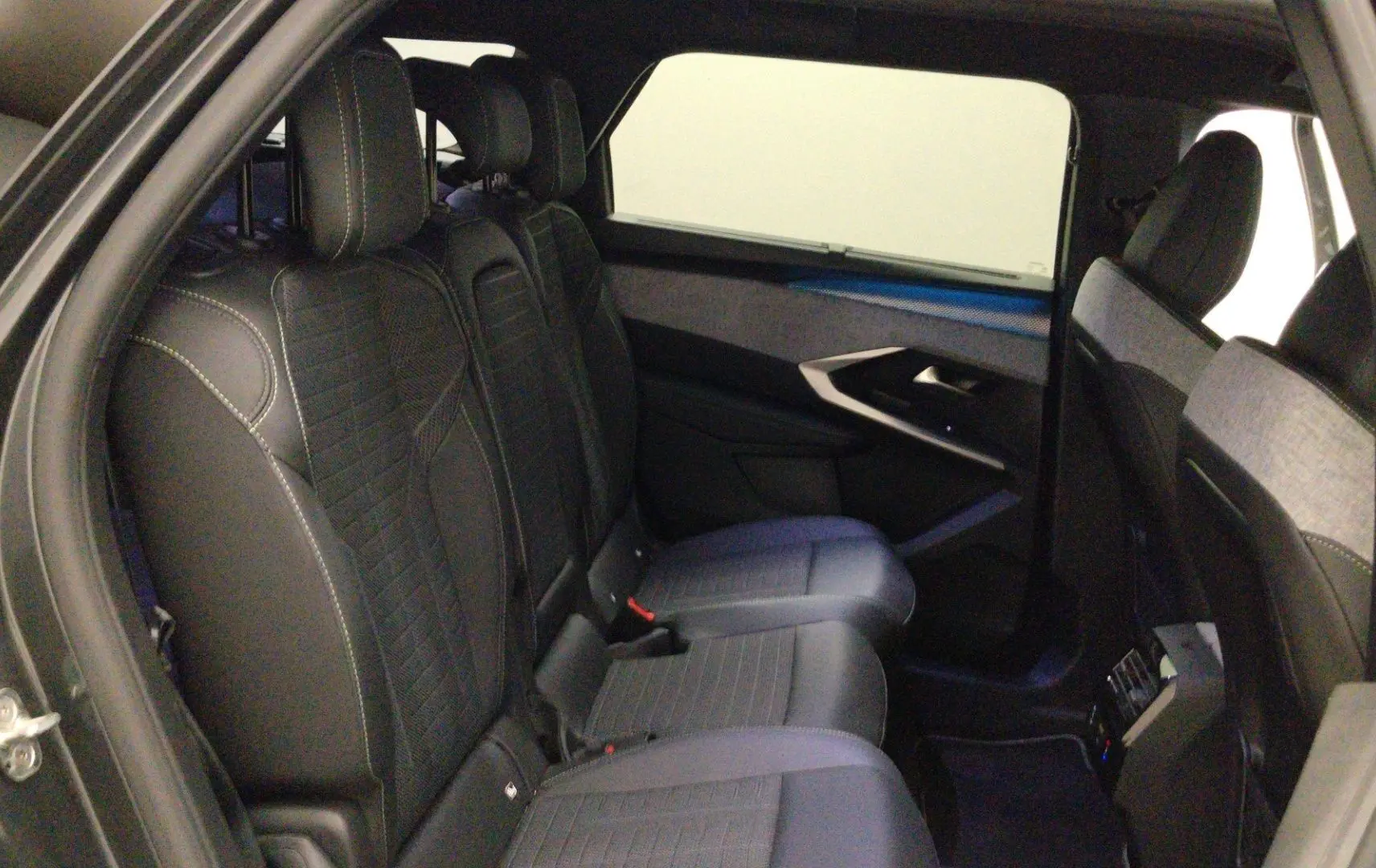 Vue intérieure côté conducteur du Peugeot 5008 III Hybrid 145 e-DCS6 GT, sièges noirs avec logo Peugeot brodé sur les appuie-têtes.