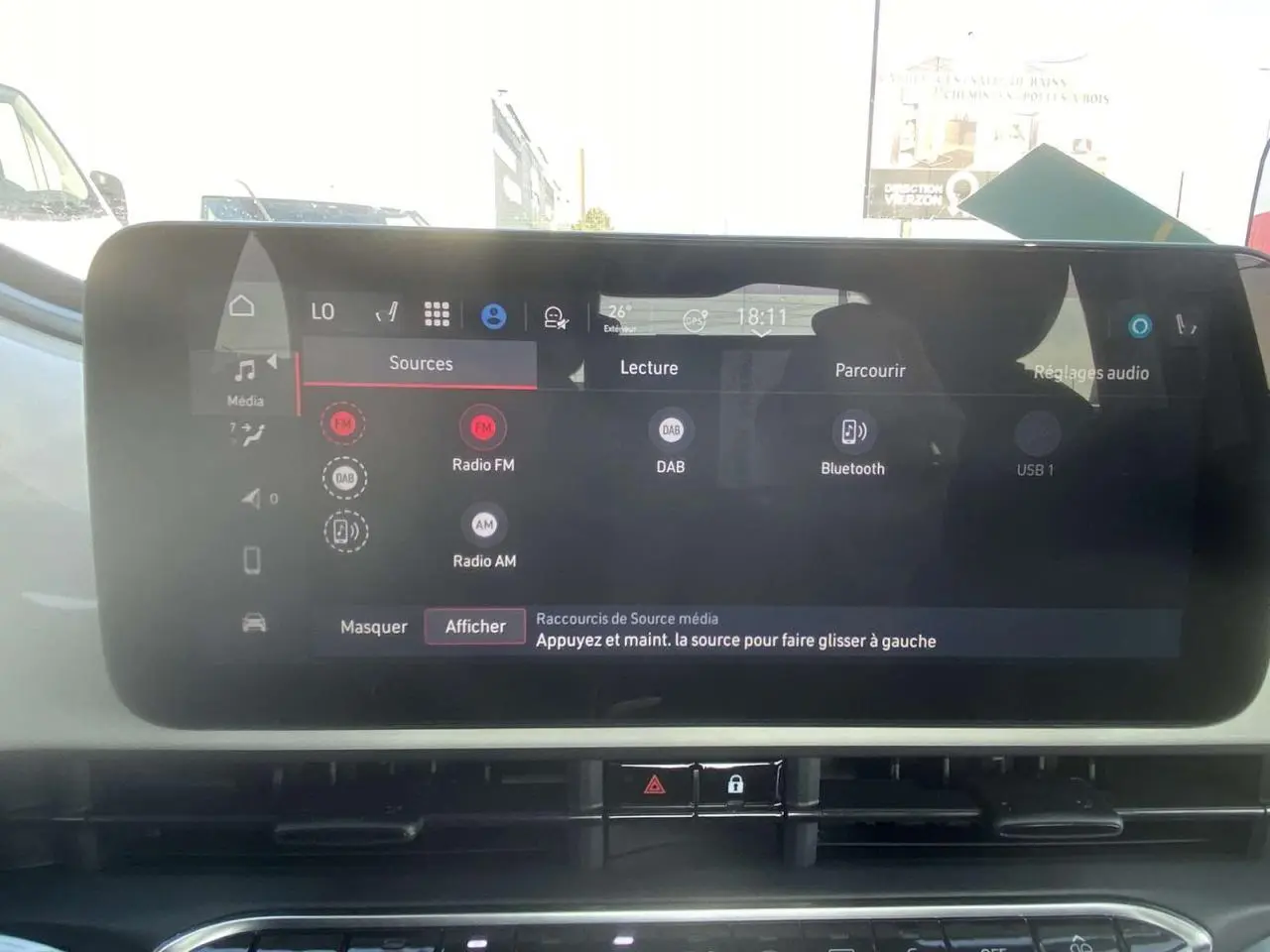 Écran tactile central de la Fiat 500 Électrique 2022, affichant les options audio avec tableau de bord blanc en arrière-plan.