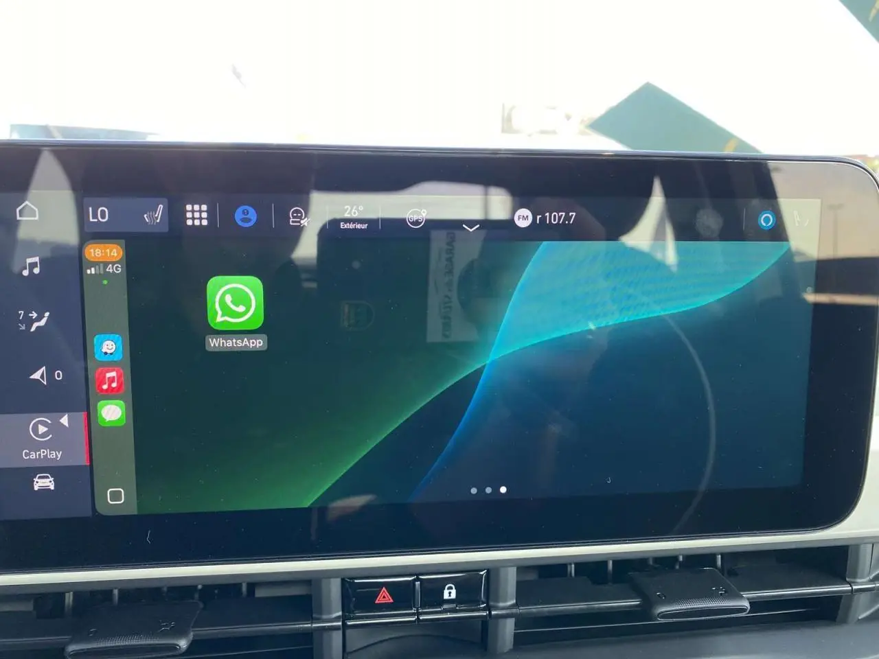 Écran tactile central de la Fiat 500 Electrique blanche 2022 affichant l'interface Apple CarPlay avec WhatsApp ouverte.