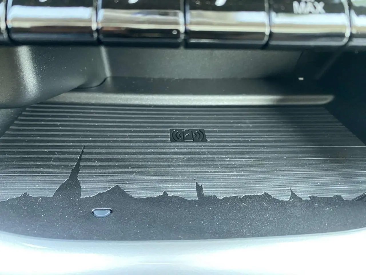 Gros plan sur le chargeur à induction noir avec motif de skyline, intérieur de la Fiat 500 électrique blanche 2022.