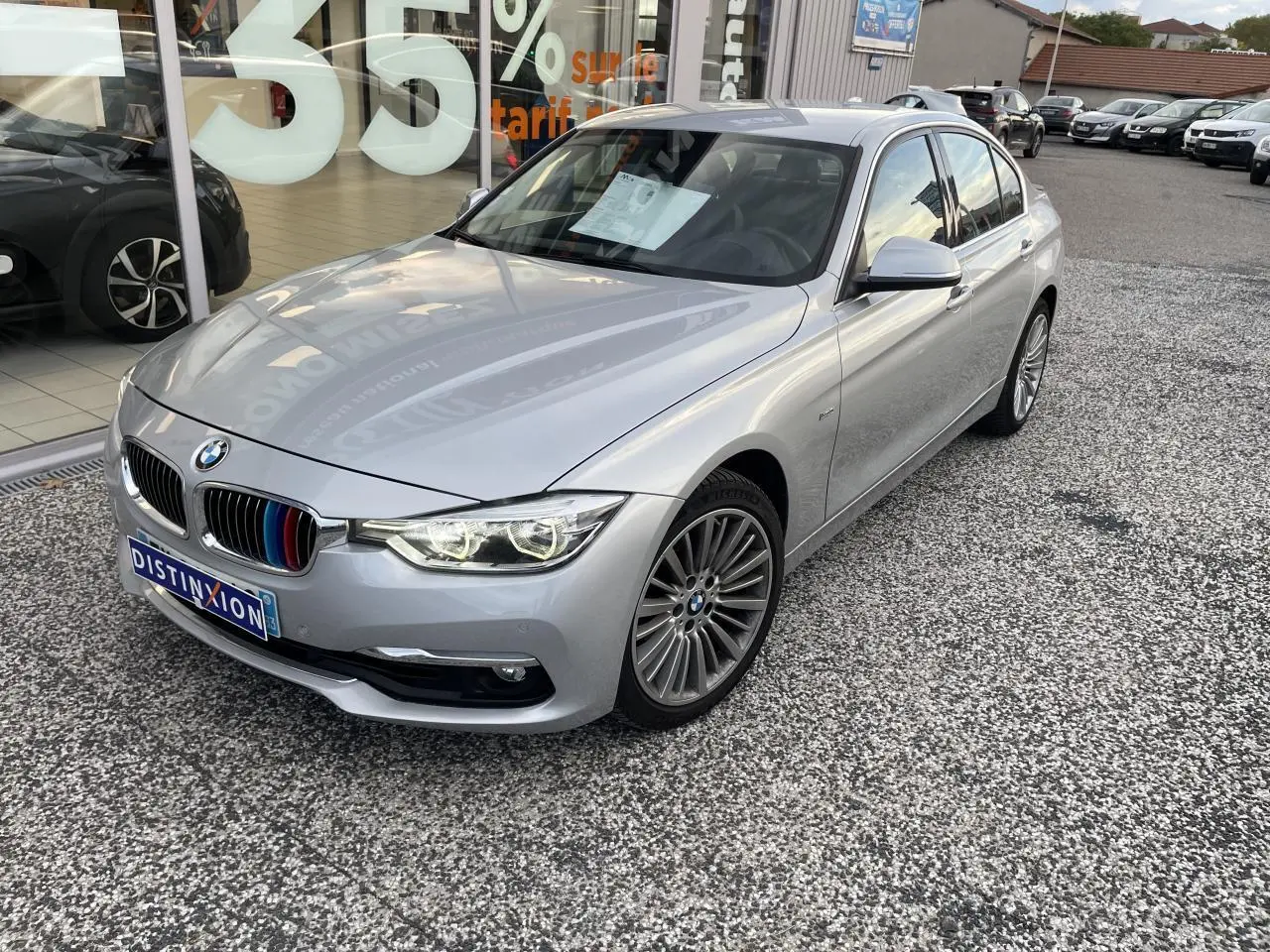 BMW Série 3 F30 gris clair vue 3/4 avant droit avec calandre ornée de liserés tricolores M