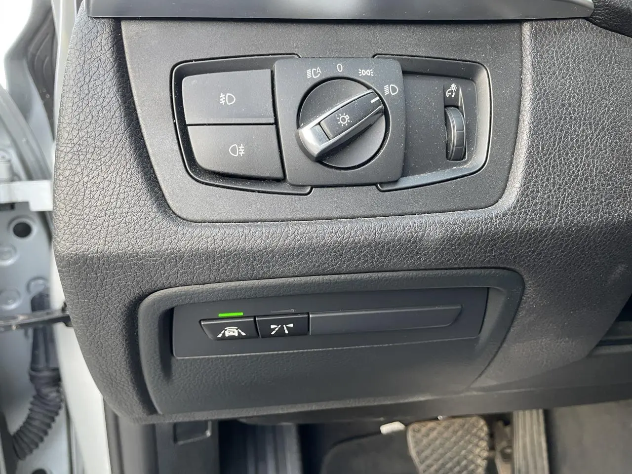 Gros plan sur les commandes d'éclairage et d'assistance au conducteur côté gauche d'une BMW Série 3 F30 gris clair de 2018.