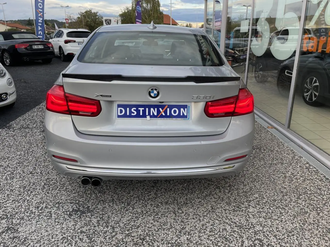 Vue arrière d'une BMW Série 3 F30 gris clair 330i xDrive avec double sortie d'échappement et badge distinctif.