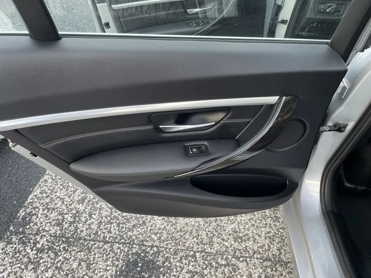 Porte arrière droite ouverte d'une BMW Série 3 F30 gris clair, avec garniture noire et insert décoratif brillant.