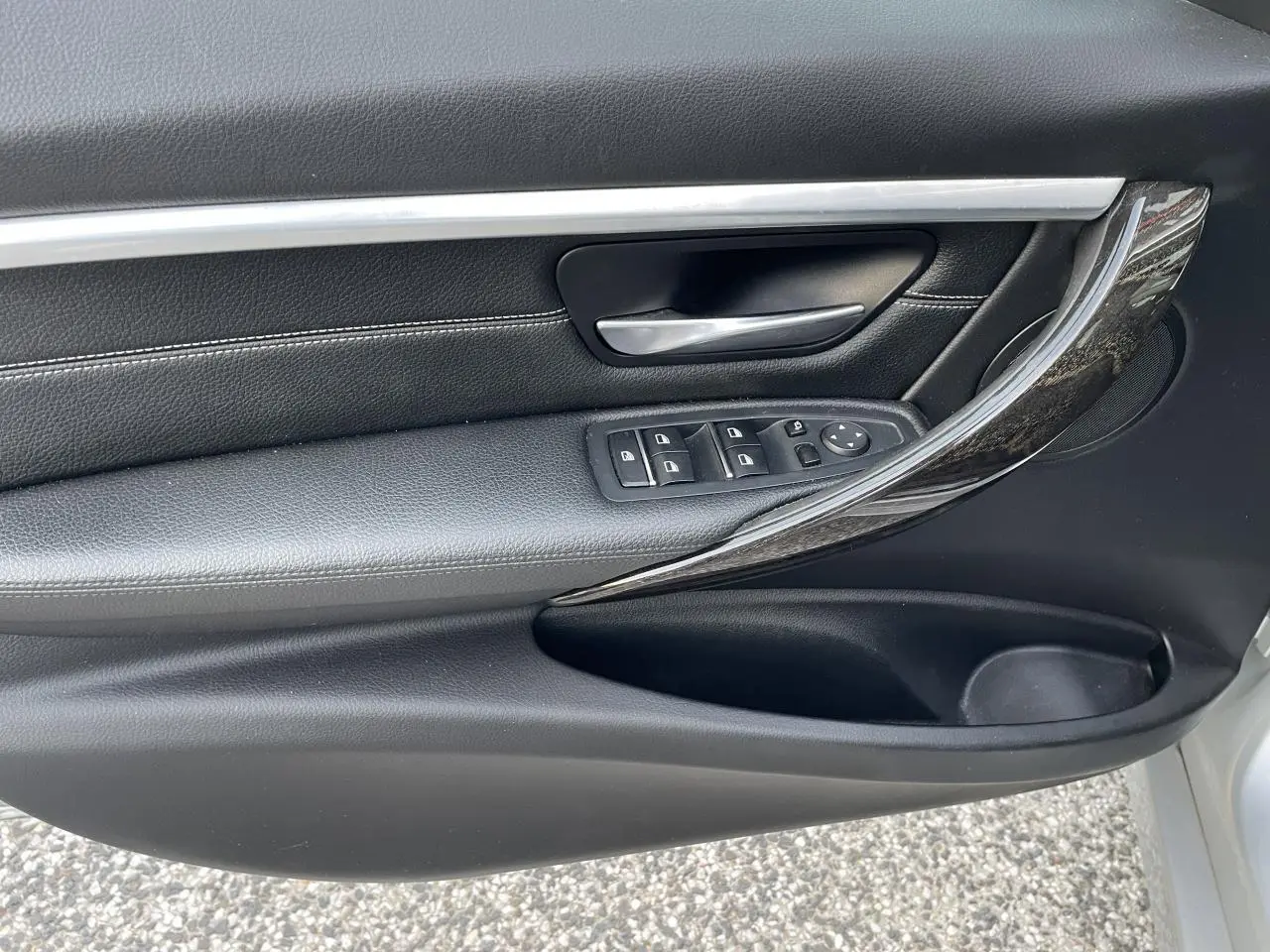 Poignée intérieure côté gauche de porte BMW Série 3 F30 gris clair avec garniture cuir noire et insert chromé brillant.