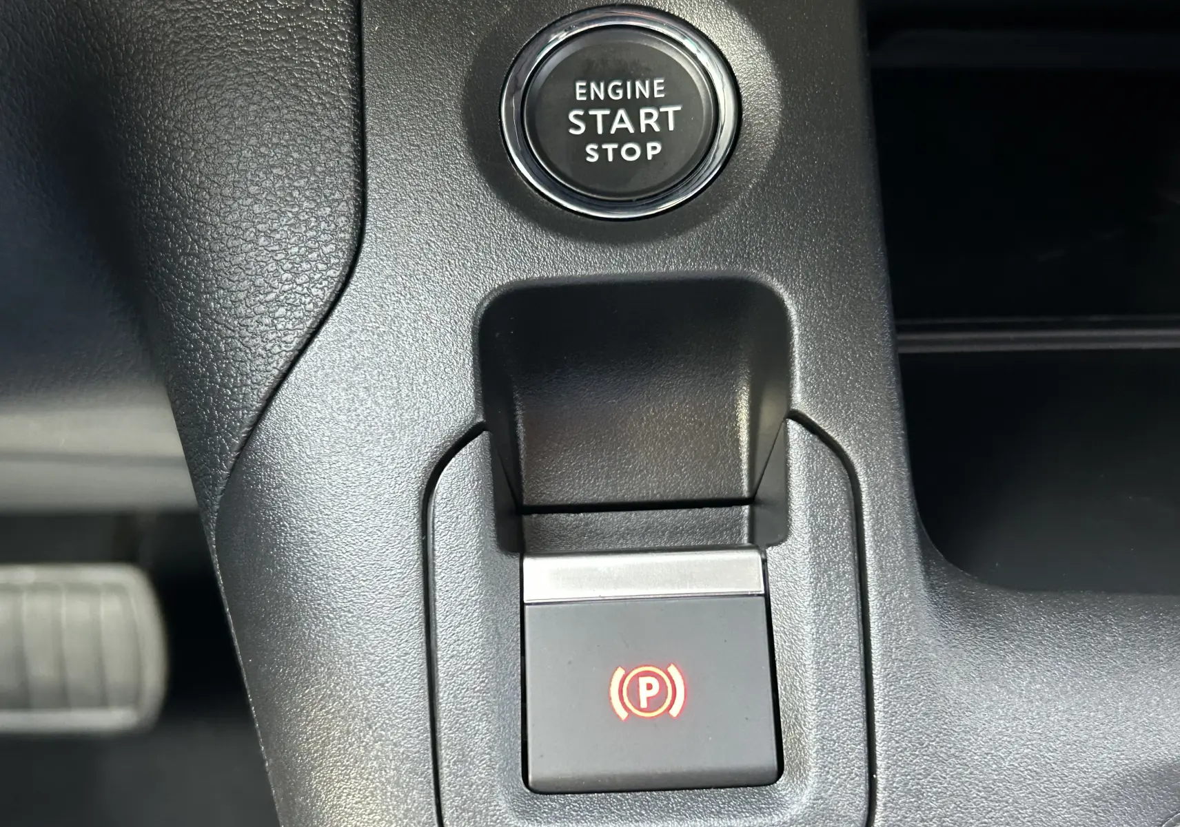 Gros plan sur le bouton de démarrage et la commande de frein à main électrique dans l'habitacle du Peugeot Partner Fourgon blanc.