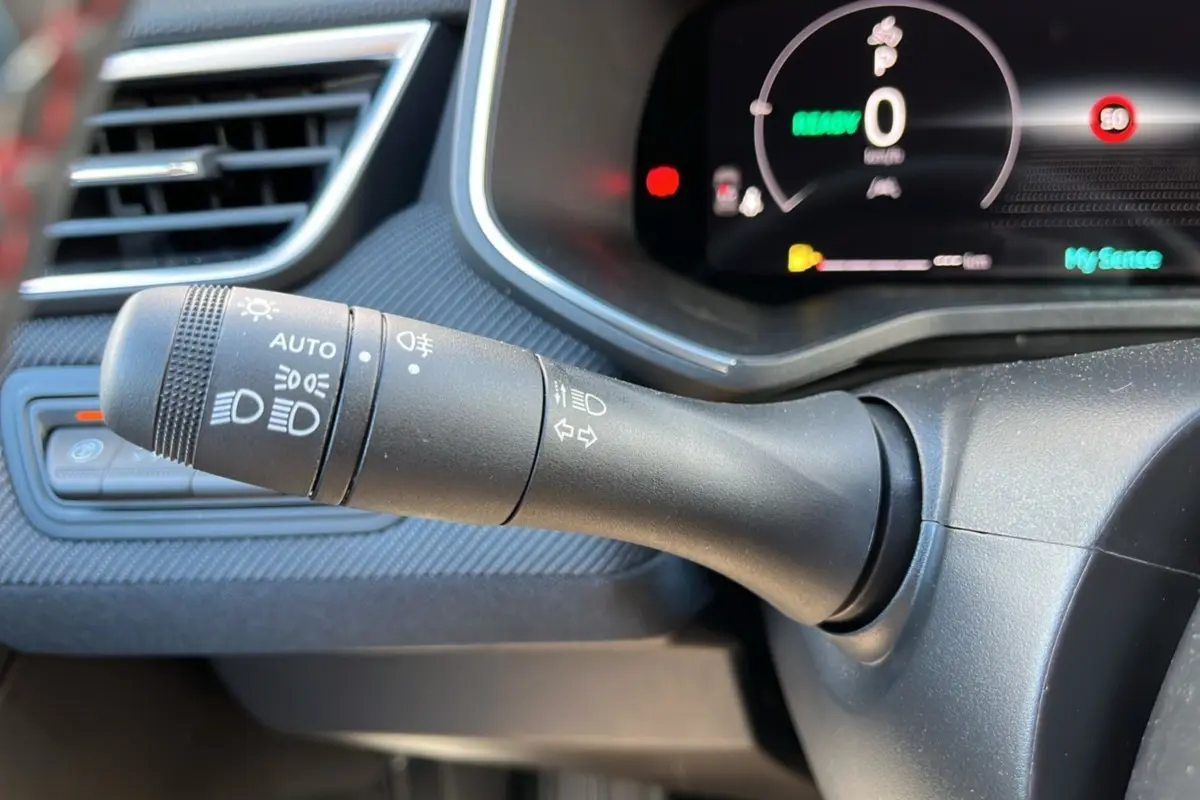 Gros plan sur la commande des feux et clignotants à gauche du tableau de bord de la Renault Clio V E-Tech 145 Esprit Alpine Bose.