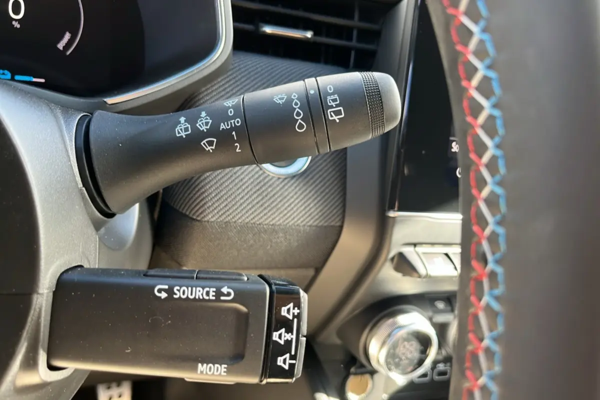 Détail de la commande d’essuie-glace et multimédia sur le volant cuir tricolore d’une Renault Clio gris schiste, intérieur avant.