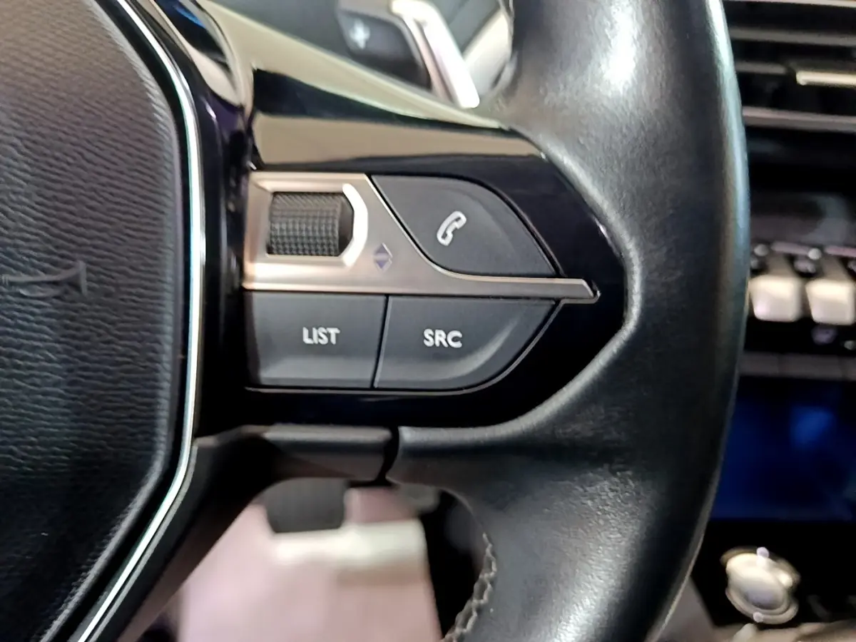 Gros plan sur les commandes gauche du volant noir du Peugeot 3008 blanc hybride rechargeable, version 2020 Allure.